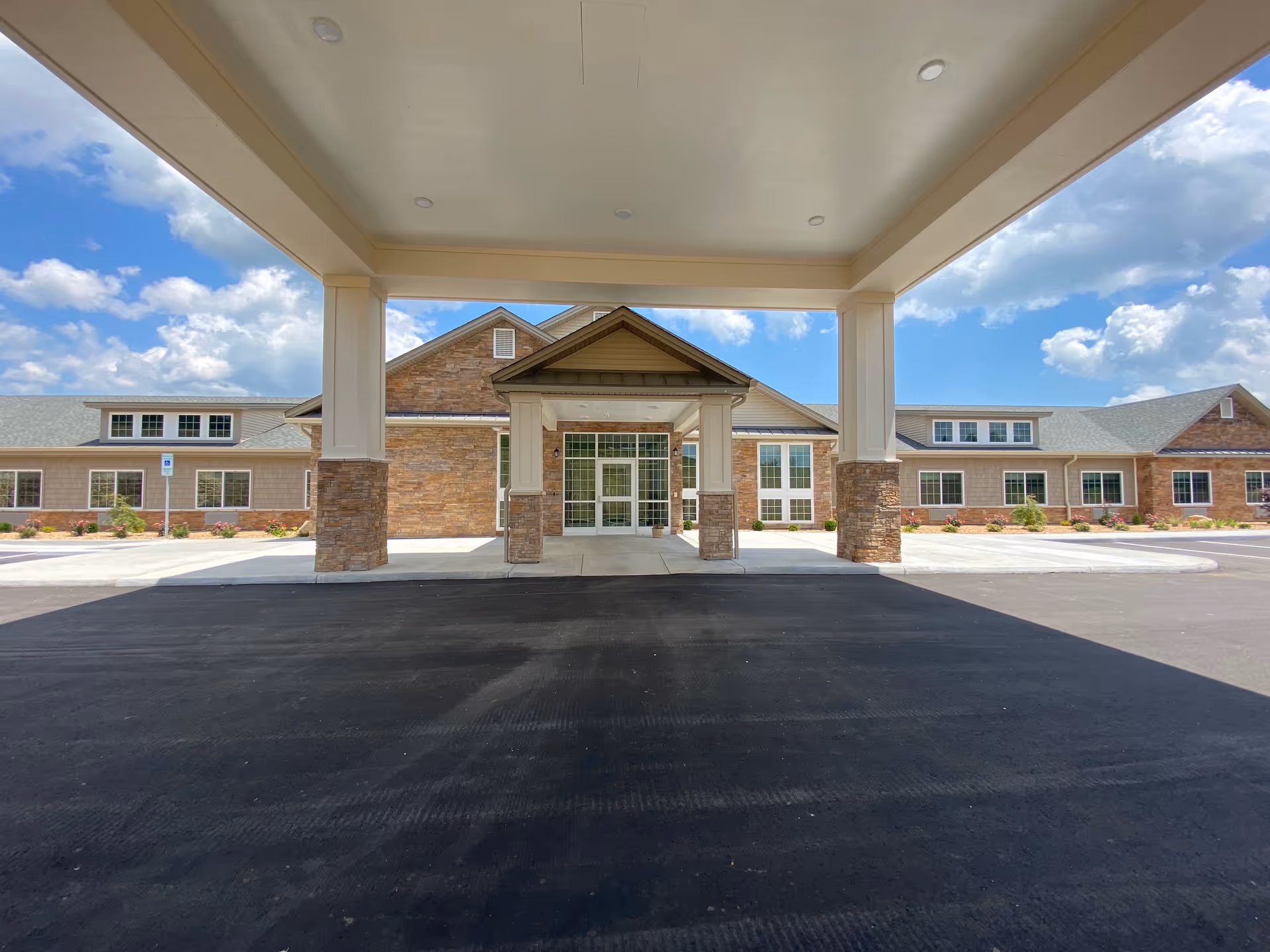 Front entrance of a brick-and-stone senior living facility with a covered porte-cochere.
