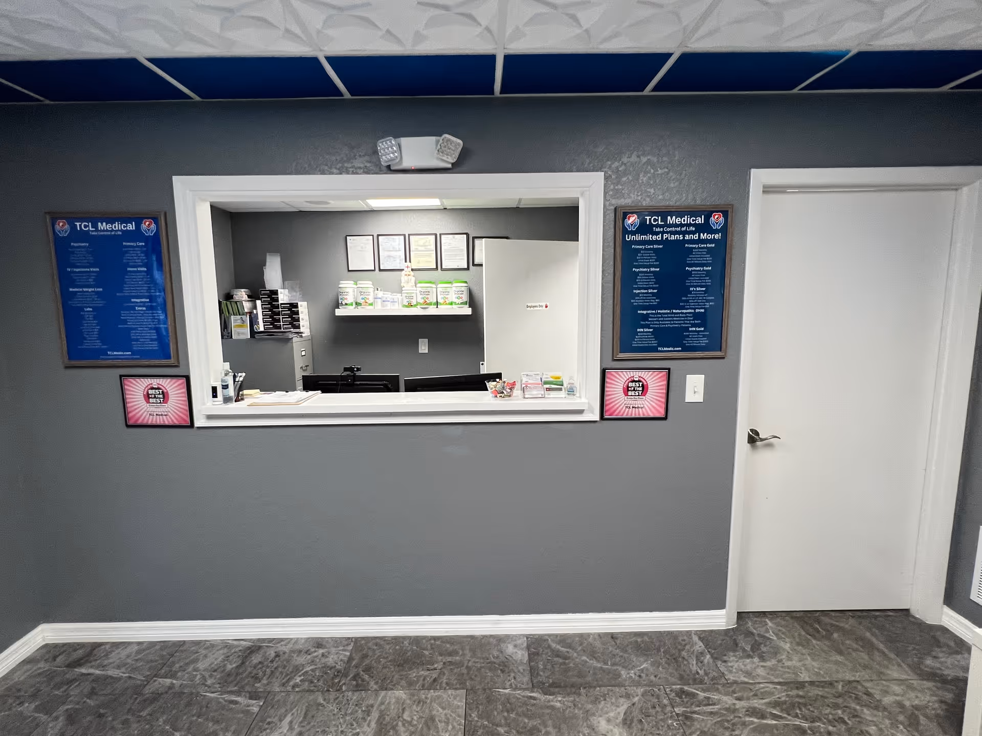 A TCL Medical interior reception area with a service window, counter, and framed posters.