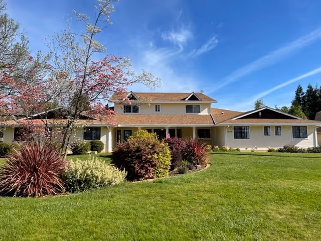 Sunshine House senior living facility with a manicured lawn and blue sky.