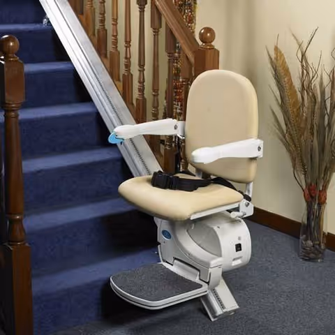 A beige stairlift chair installed beside carpeted stairs in a senior living facility.
