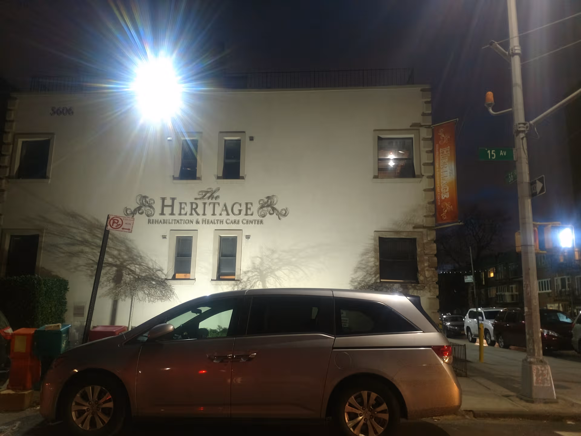 Night exterior view of The Heritage building with a parked minivan.