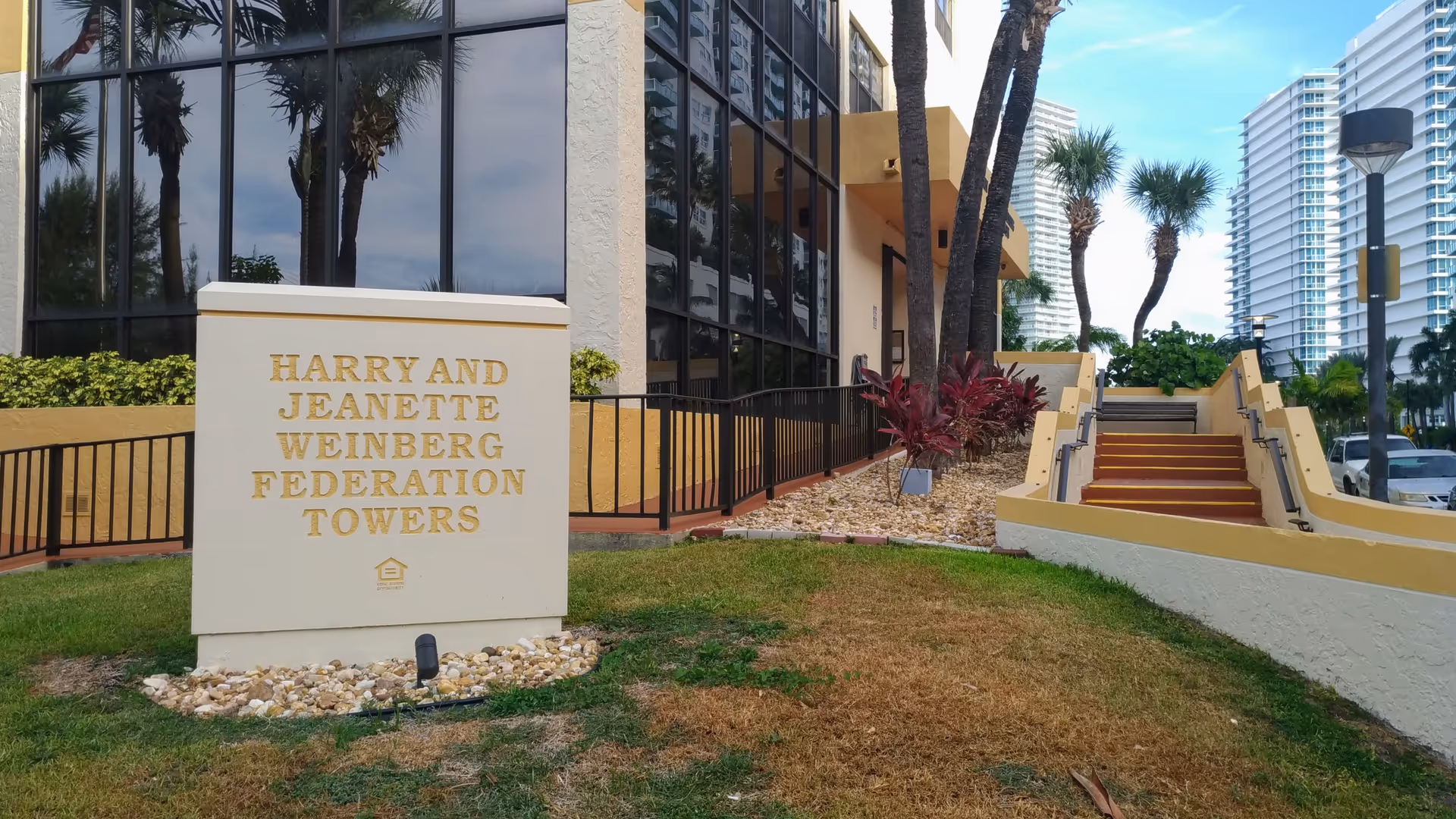 Exterior view of Federation Towers entrance with sign and steps.