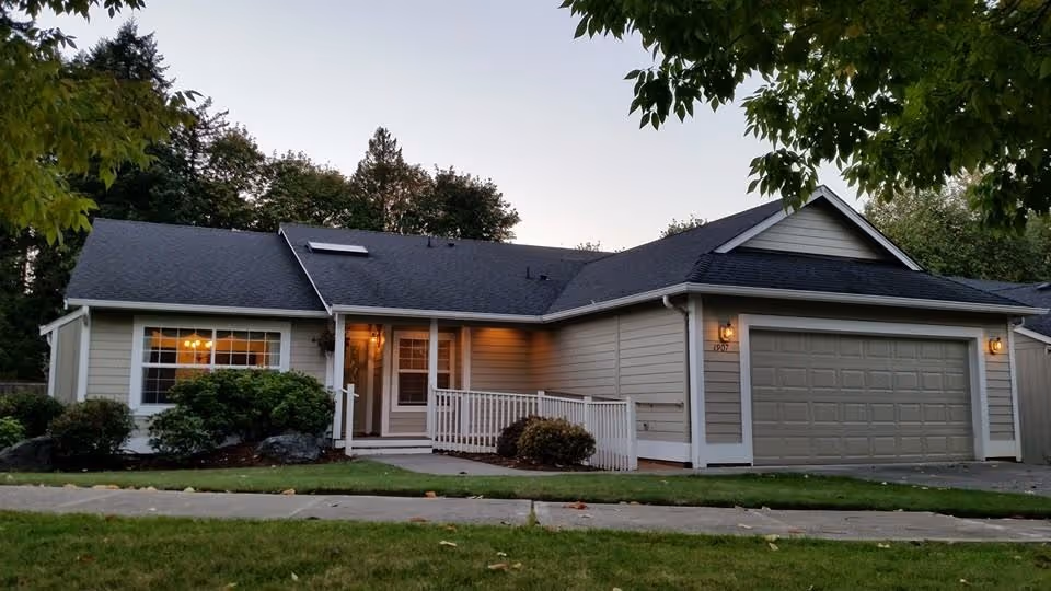 Single-story suburban senior living facility with a front porch and attached two car garage.