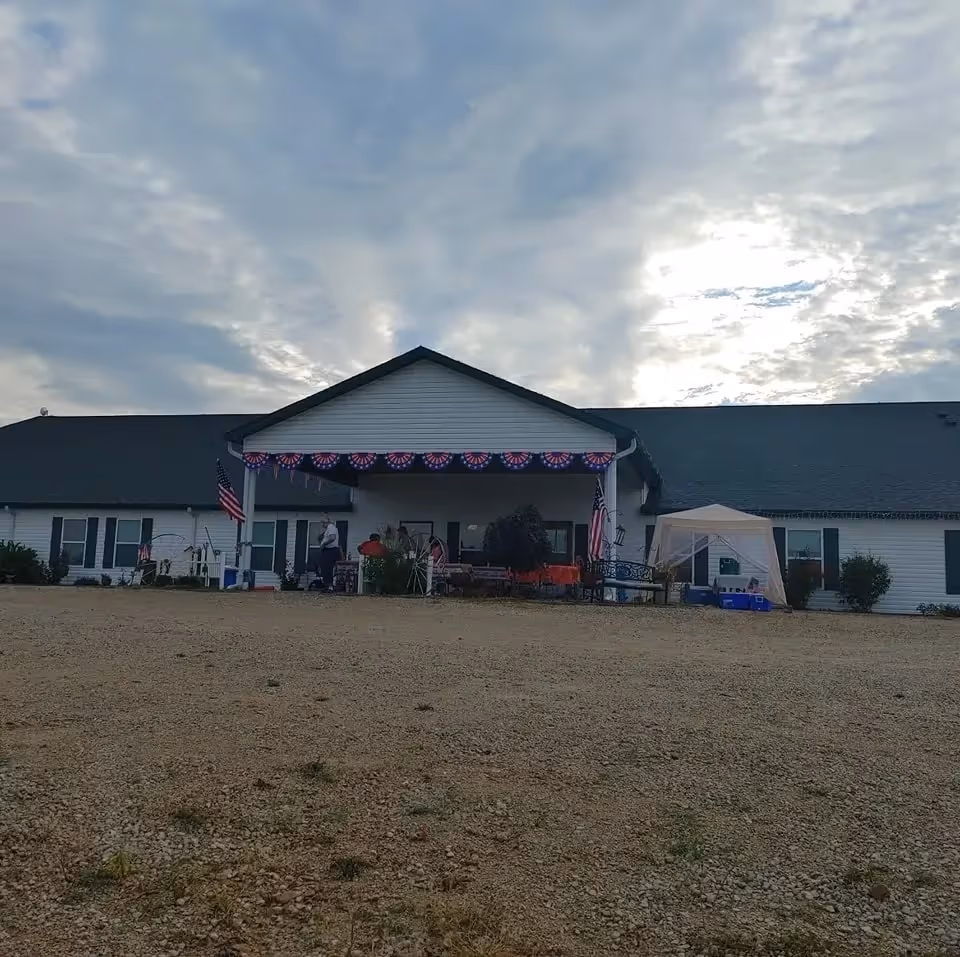 Exterior view of Annie's House with a covered front porch, bunting, flags, and outdoor seating.
