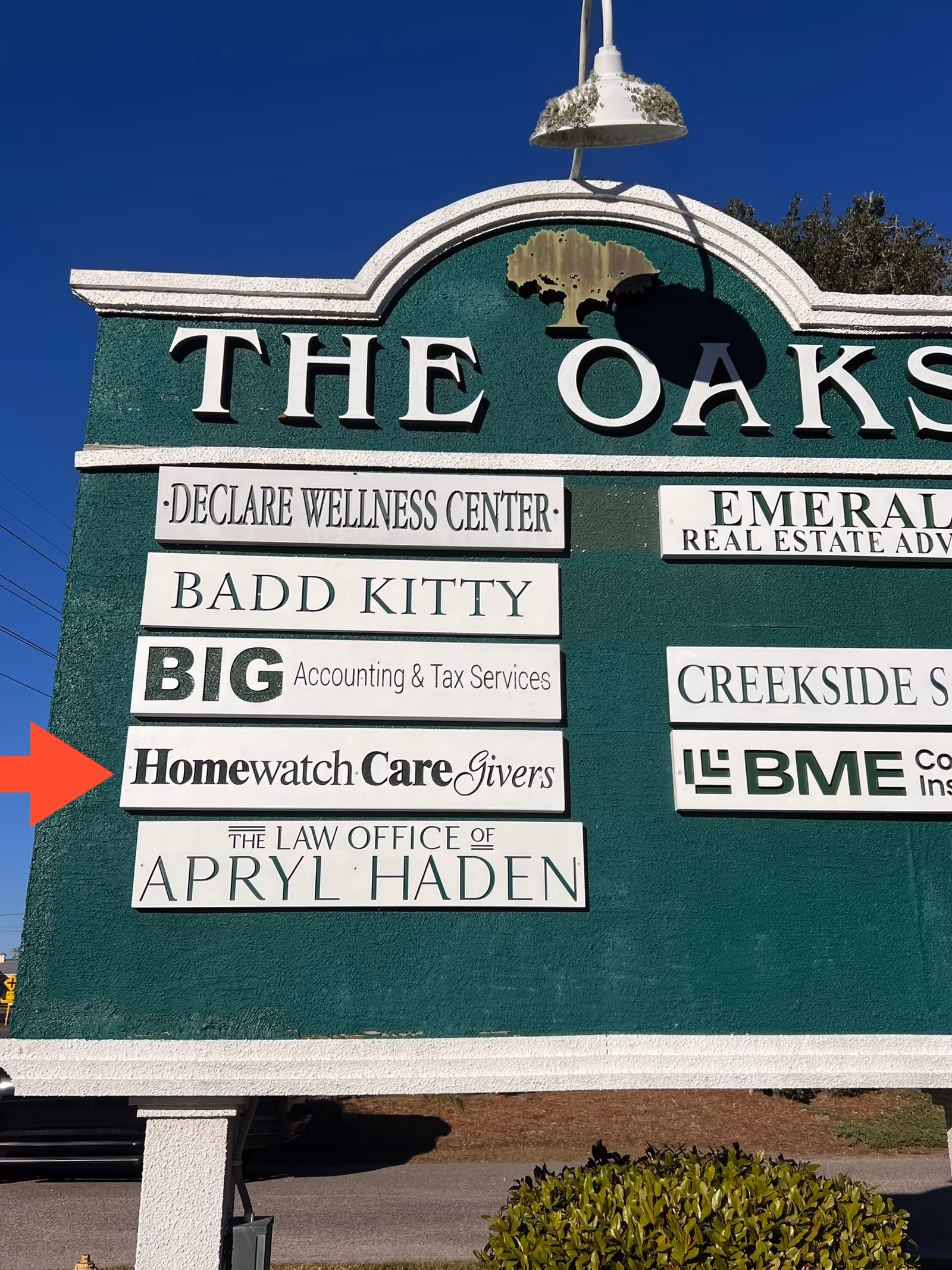 Exterior signboard with multiple business names including Homewatch CareGivers and The Oaks.
