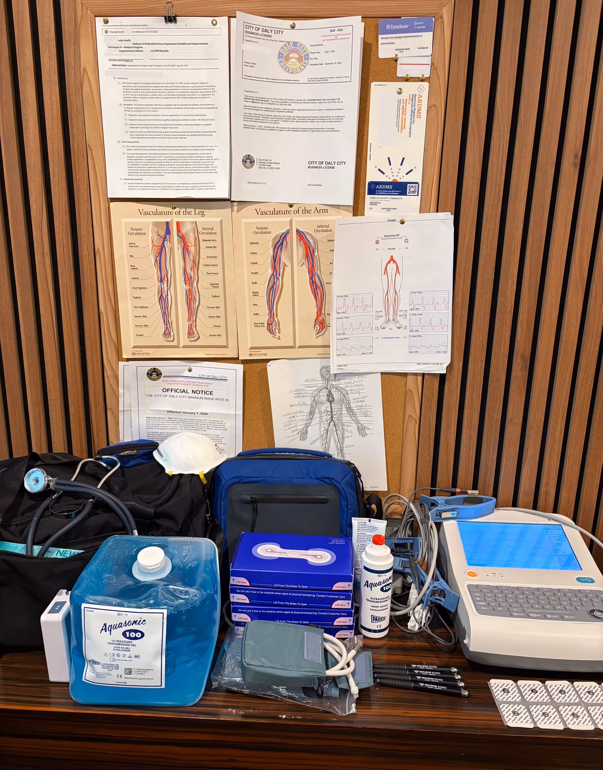 Medical equipment and charts on a desk against a corkboard in an office.