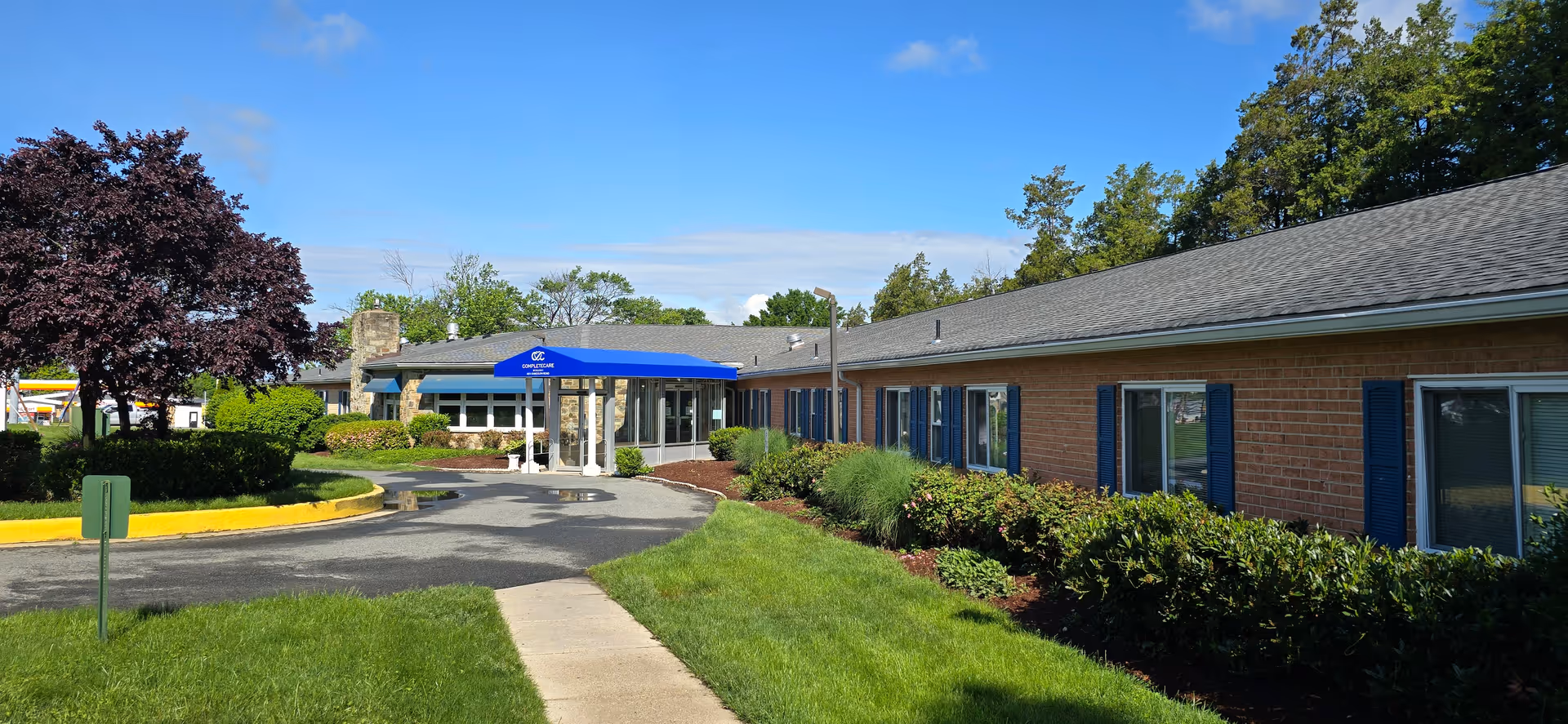 Single story brick senior living facility with blue shutters and front entrance canopy.