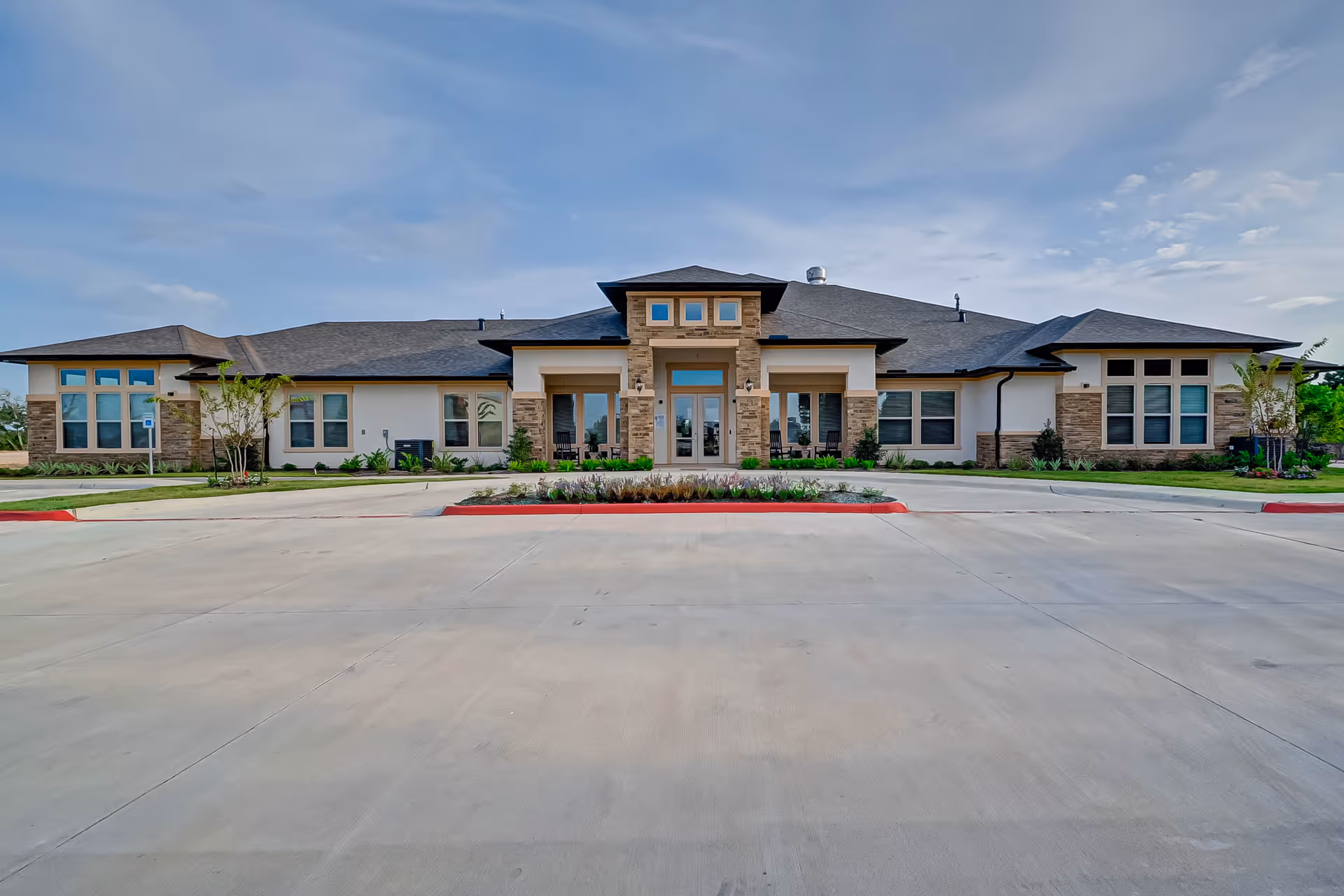 Modern single-story senior living facility with stone accents and a landscaped entrance.