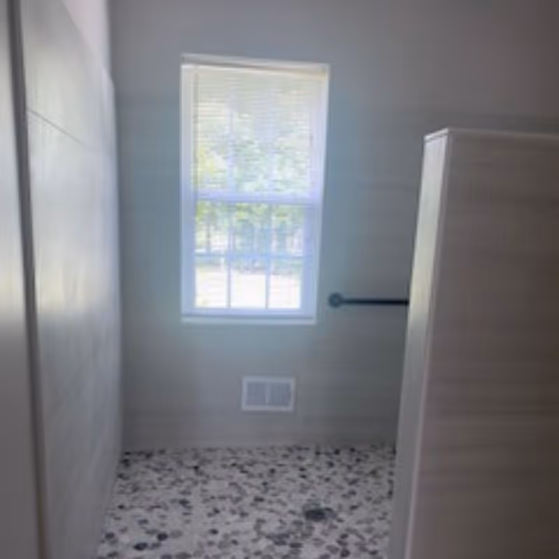 Bright bathroom with a window, tiled floor, and a grab bar along the wall.