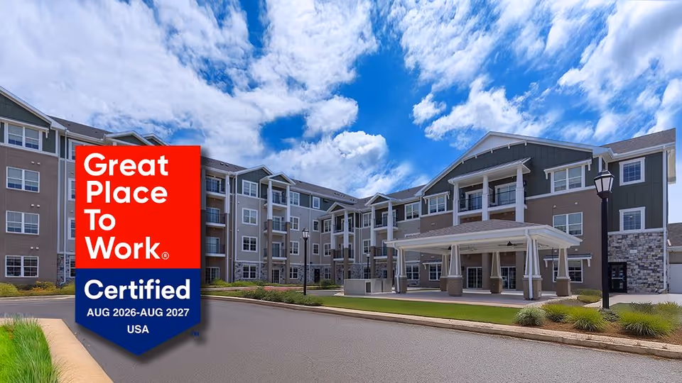 Exterior view of a senior living facility with a covered entrance and a certification badge.