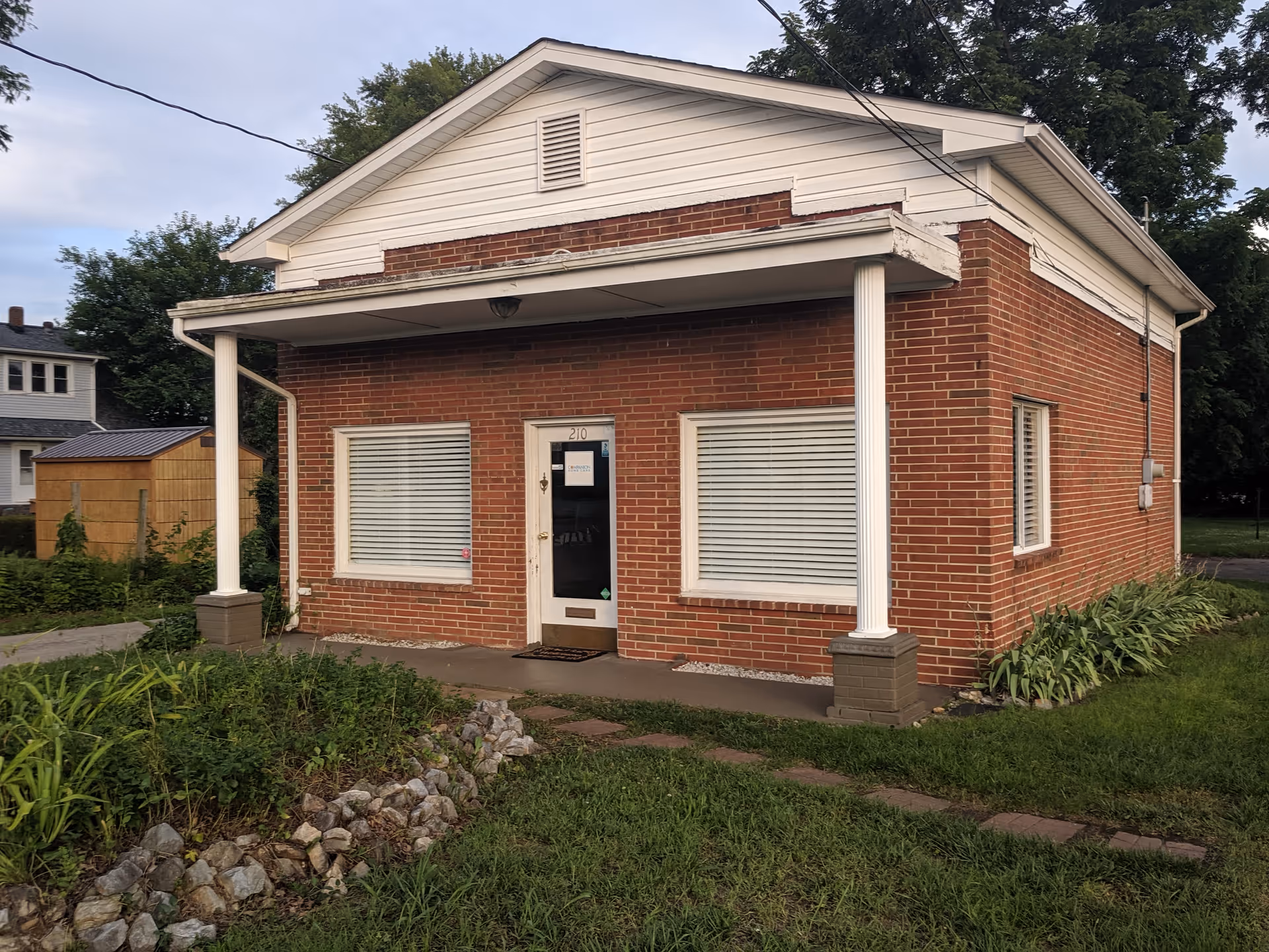 Brick one-story building with white trim, front porch columns, and a central door.