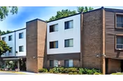 Overture San Marcos exterior: a three-story brick and white siding building with windows and landscaping.