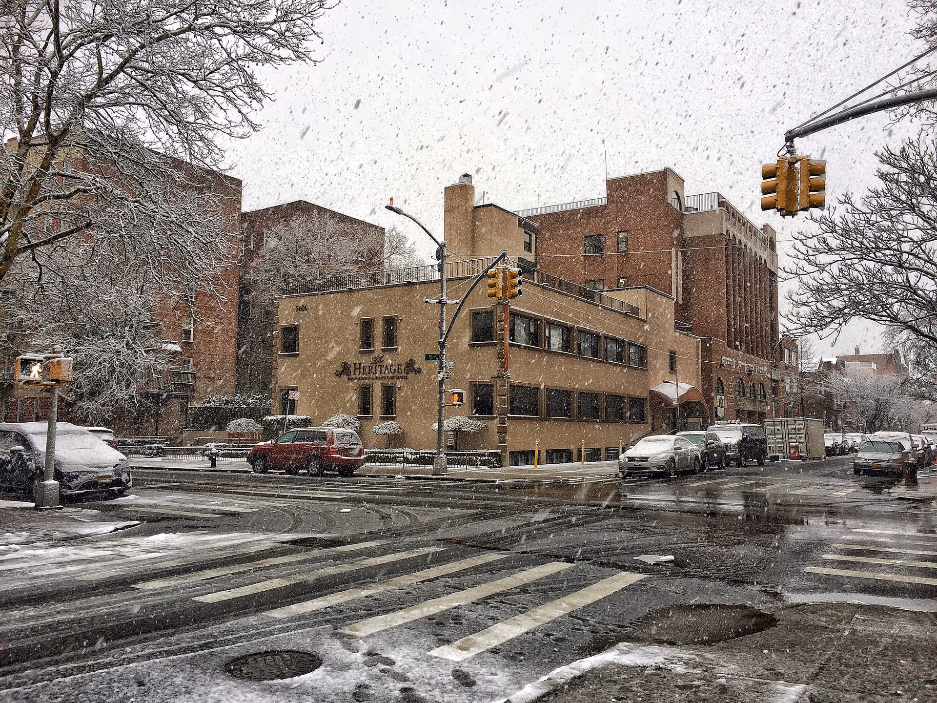 Snow falls on the Heritage Center for Rehabilitation exterior at a street intersection.