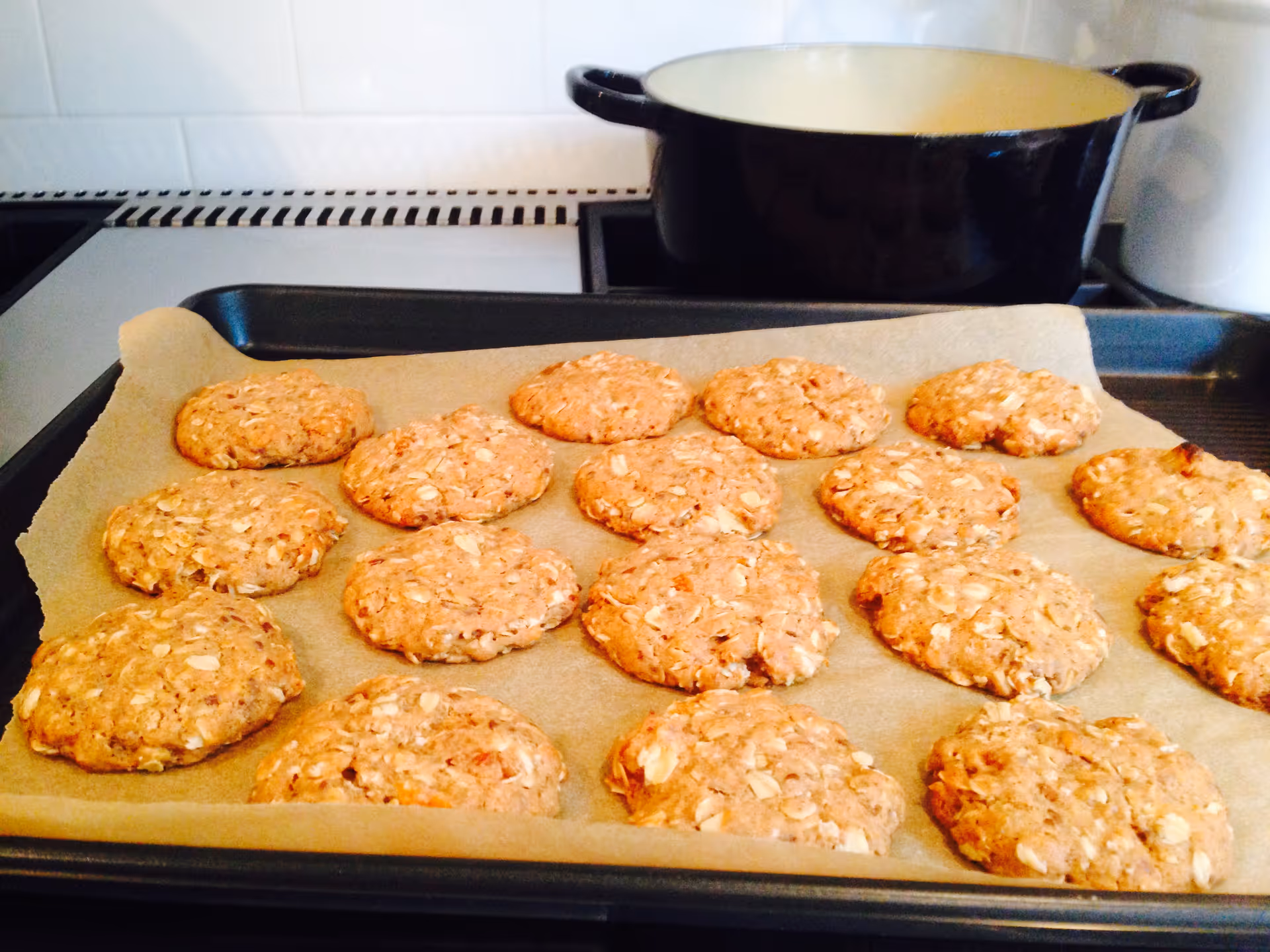 Fresh cookies on parchment-lined baking sheet cooling in a home kitchen.