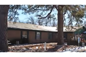 One-story brick nursing facility with large trees in the front.