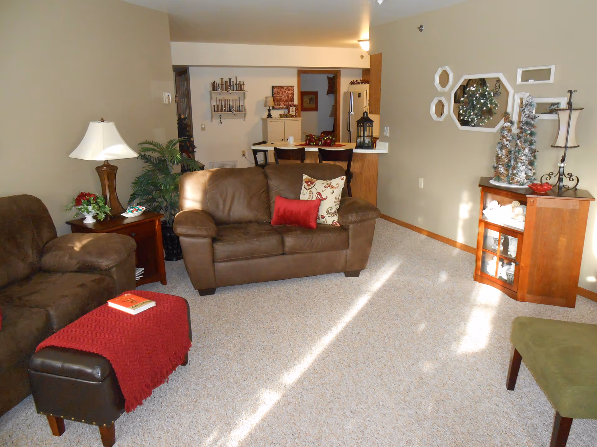 Cozy beige living room with brown furniture, decor, and a Christmas tree display.