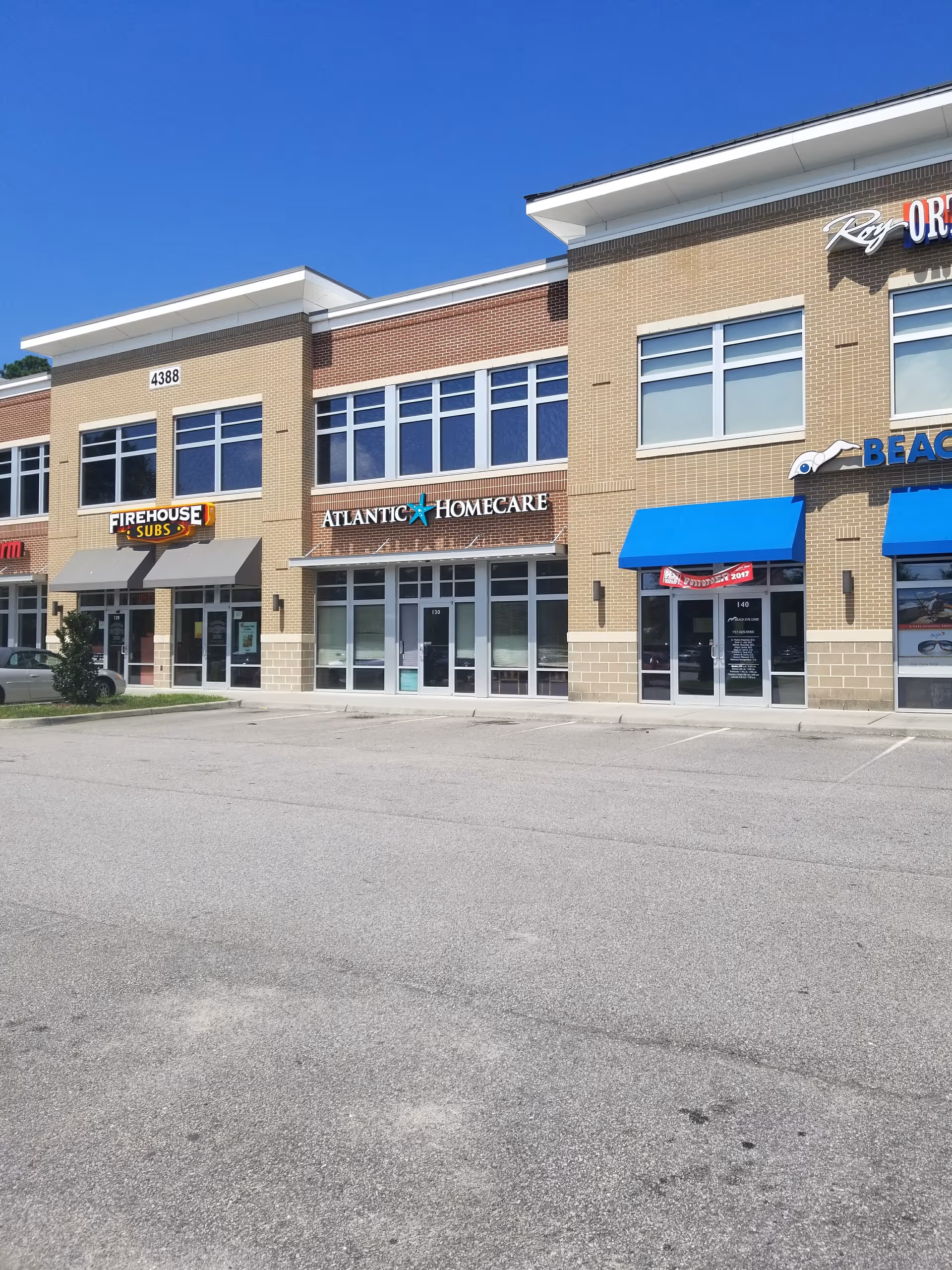 Exterior view of a strip mall with Atlantic Homecare storefront among others on a sunny day.