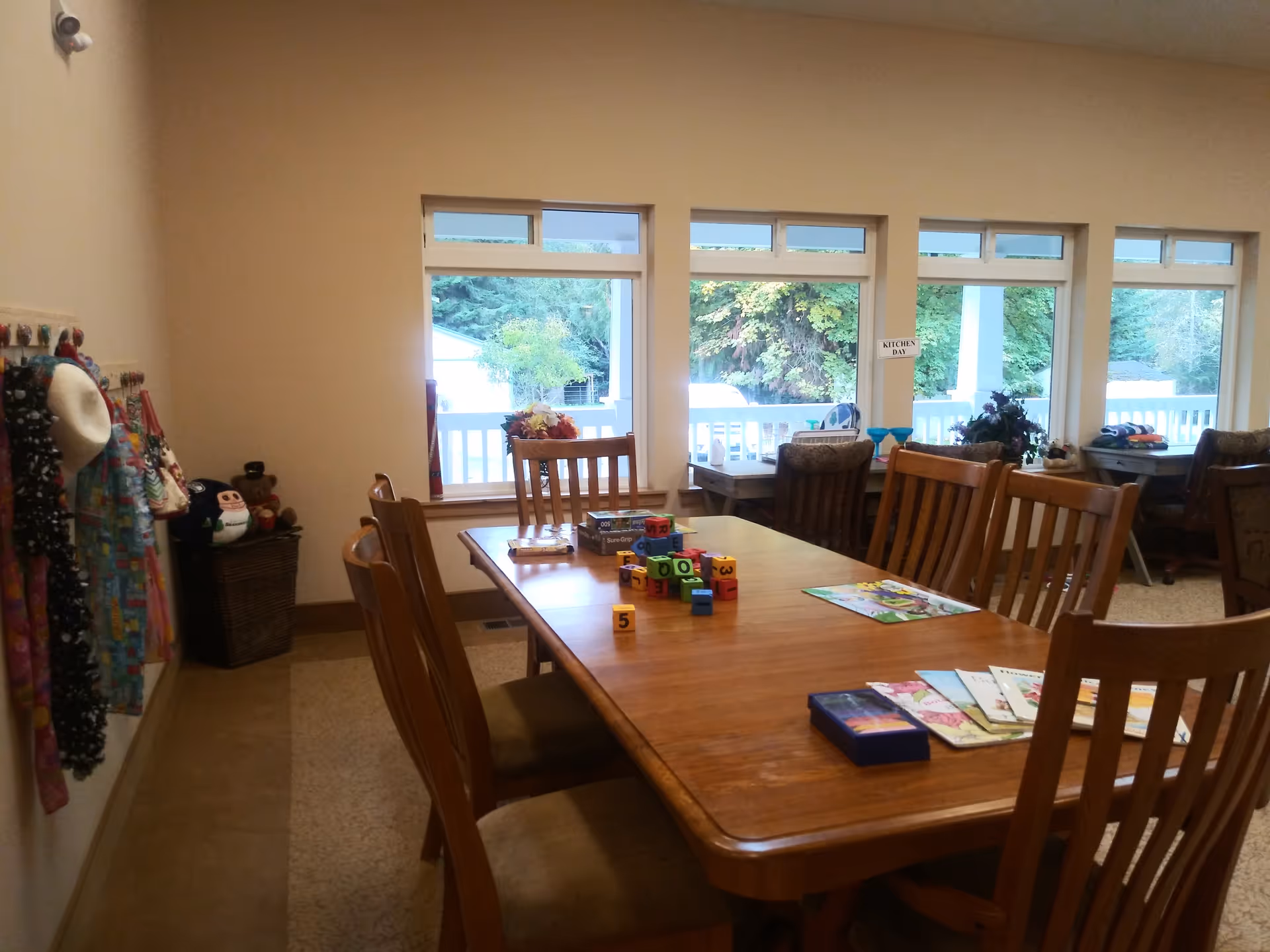 Wooden dining table with chairs in a bright room with large windows.