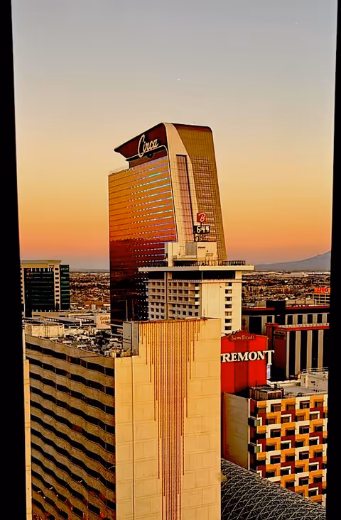Sunset over Las Vegas skyline featuring tall hotels and city buildings.
