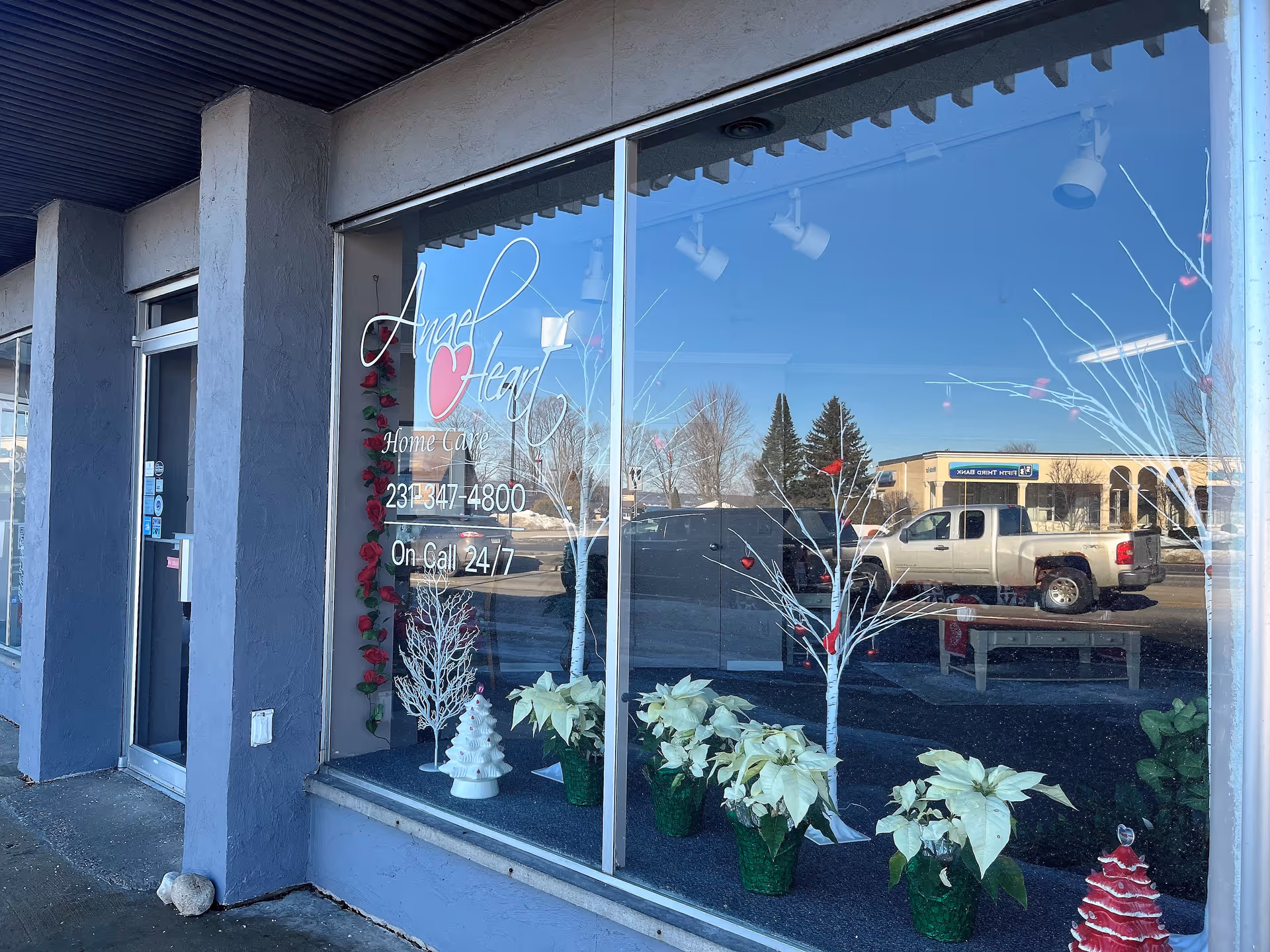 Storefront window for Angel Heart Home Care with decorative plants outside.