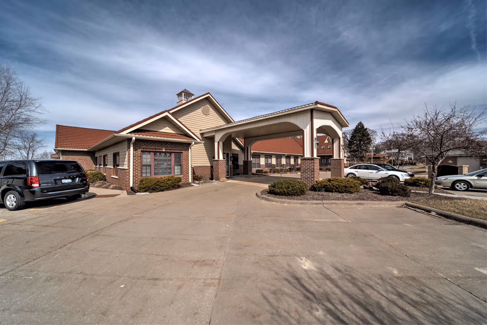 Exterior view of Charter Senior Living of Moline with a covered entrance and parked cars.
