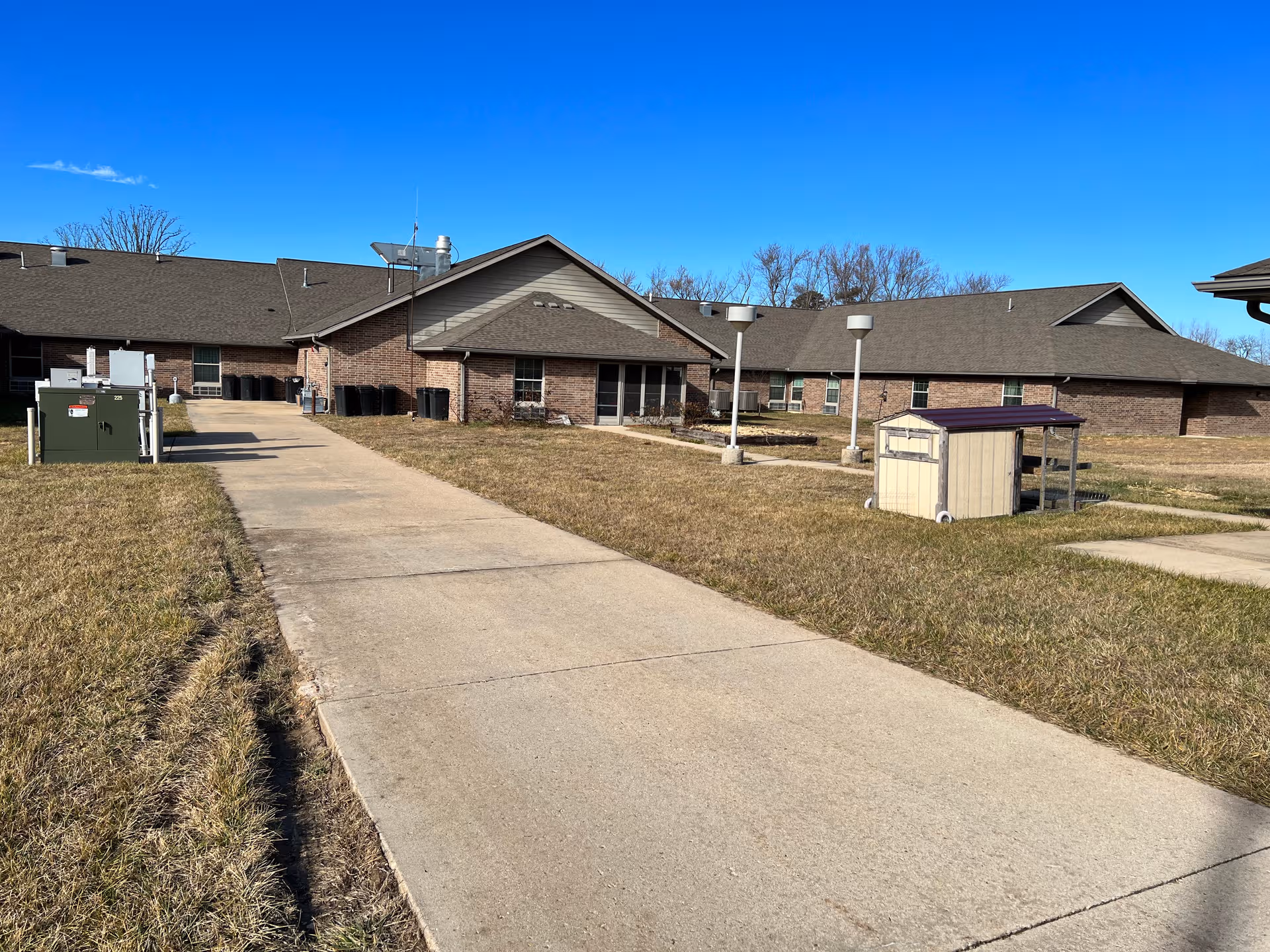 Wide view of Country Living Assisted Living building exterior with brick facade and walkway.