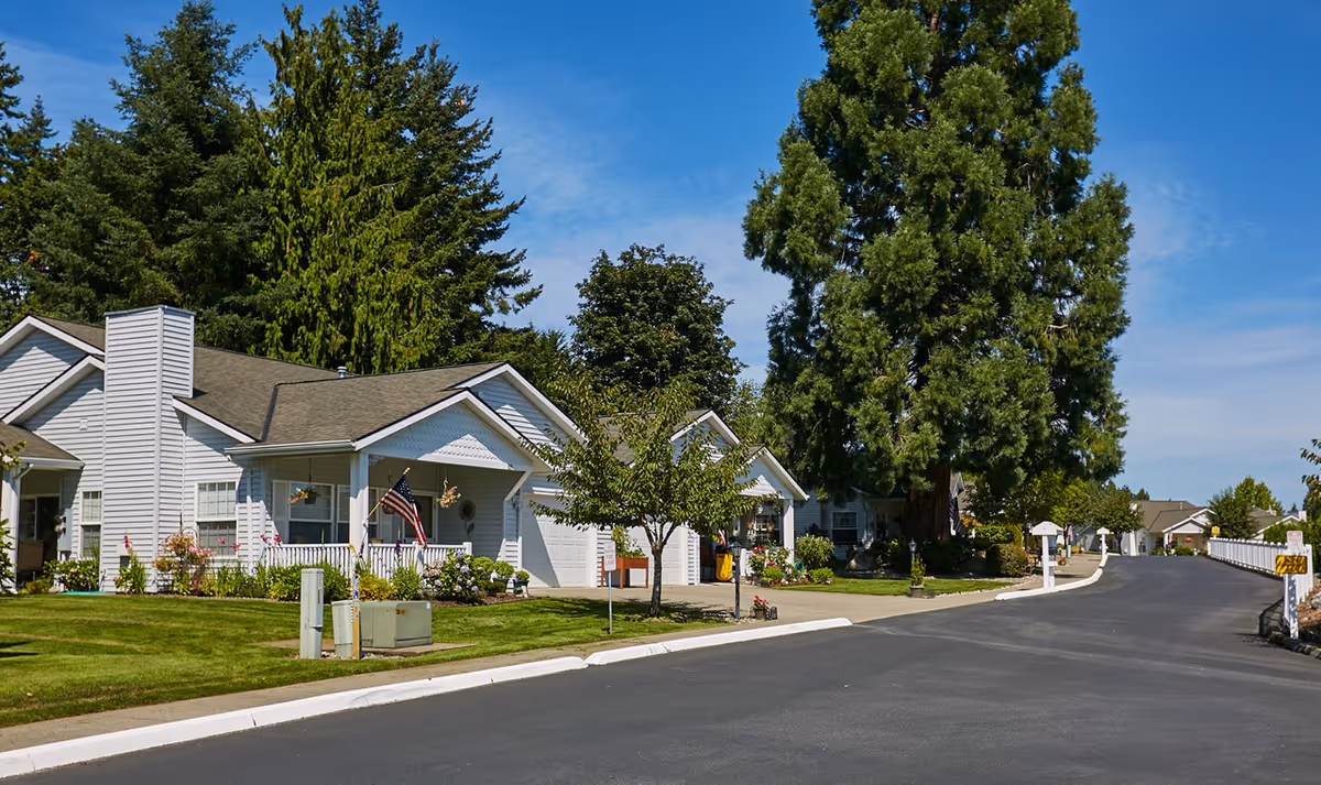 Single-story senior living cottages line a tree-lined street with green lawns.