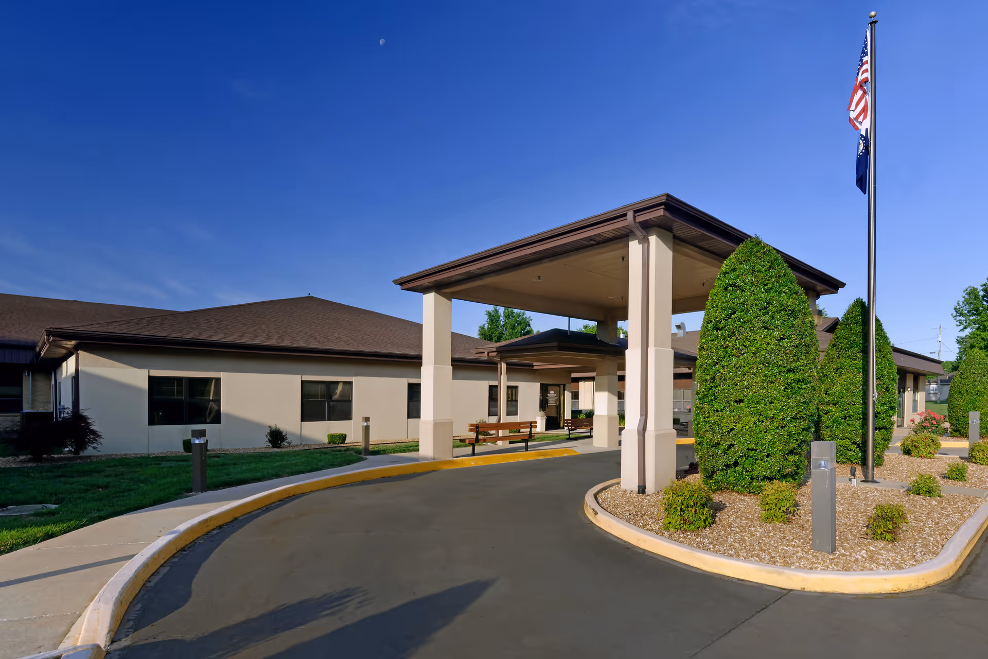 Exterior view of Citizens Memorial Healthcare Facility entrance with driveway, canopy, flagpole, and landscaping.