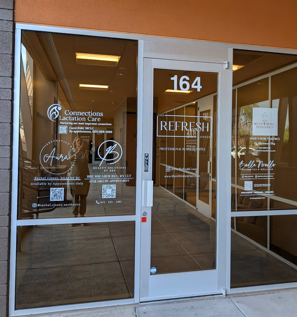 Glass storefront door with logos, orange exterior, and the number 164 displayed.