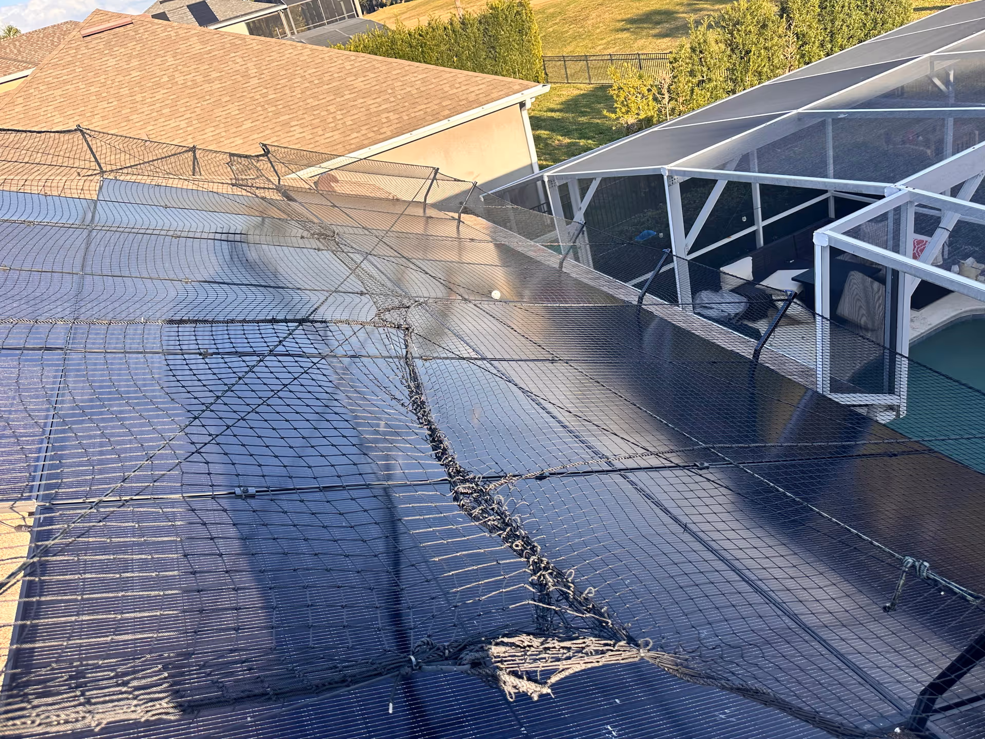 A rooftop area with barbed-wire fencing and a fenced pool enclosure under clear skies.