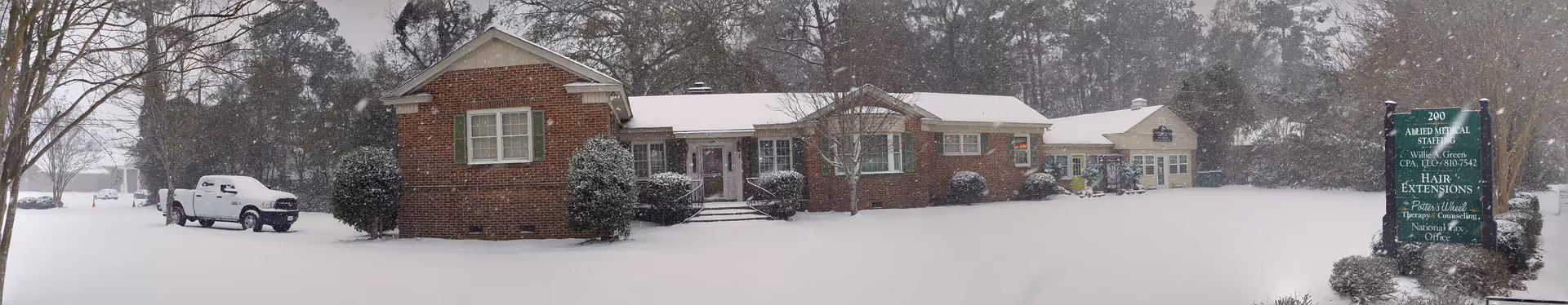 Snow-covered senior living facility with brick facade and a white SUV parked nearby.