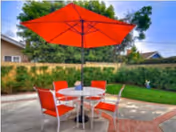 Outdoor patio with round table, red chairs, and a large red umbrella.