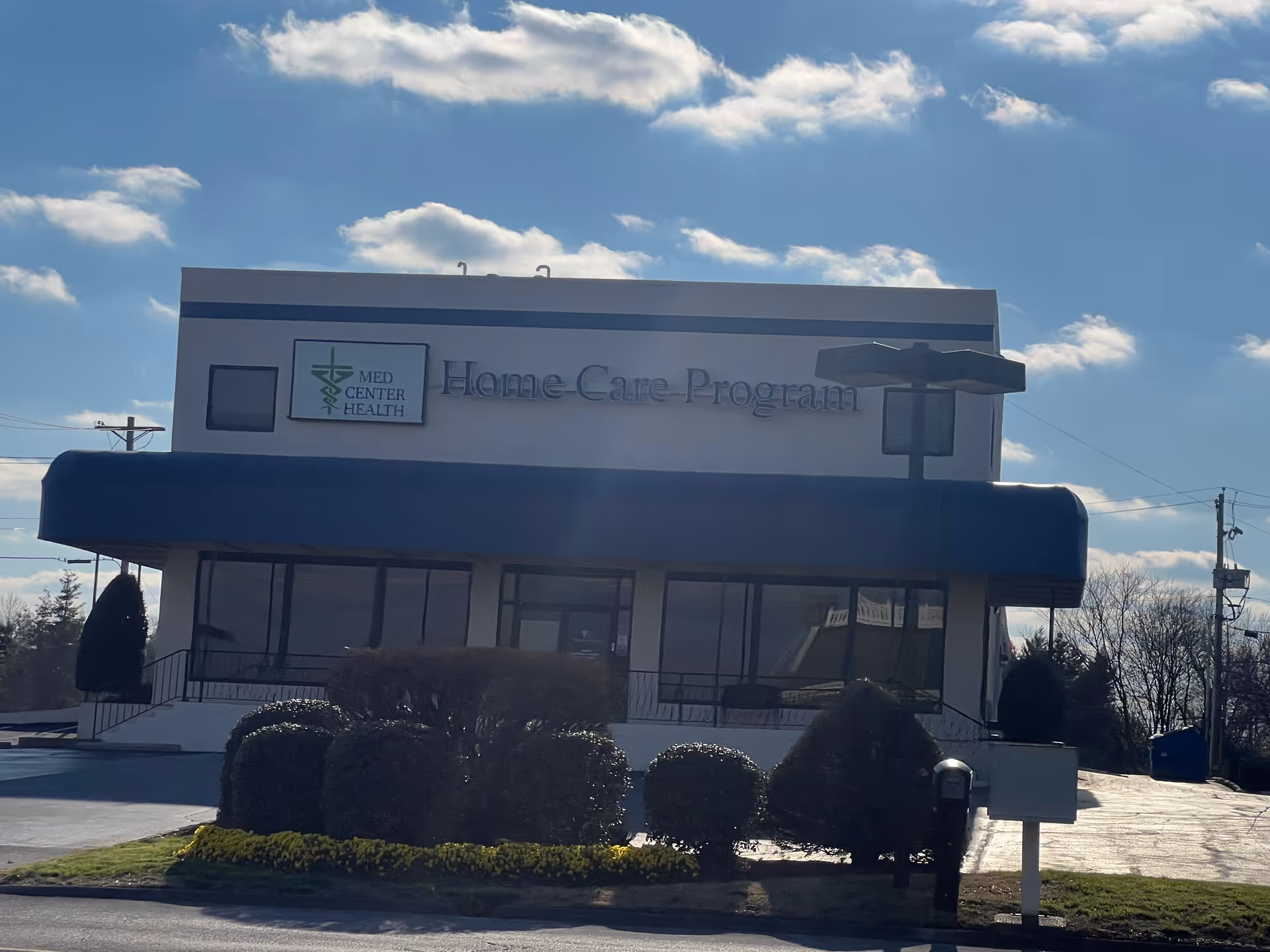 Exterior of a building with a blue awning and 'Home Care Program' sign.
