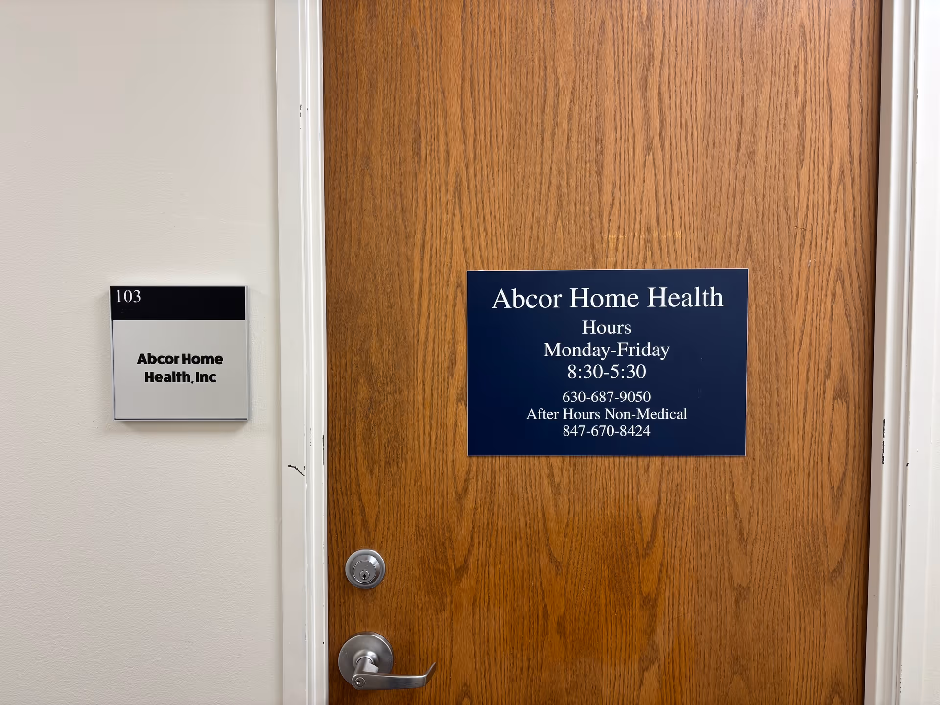 Wooden interior door bearing Abcor Home Health, Inc sign and hours plaque.