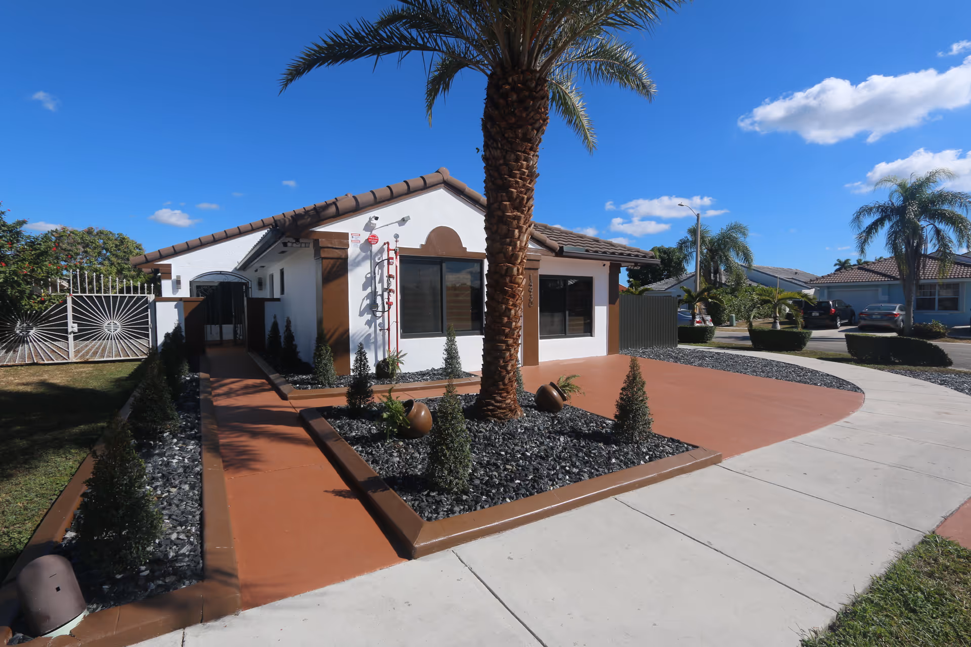 Exterior of Cruz Family ALF No 2, a white single-story building with palm trees and walkway.
