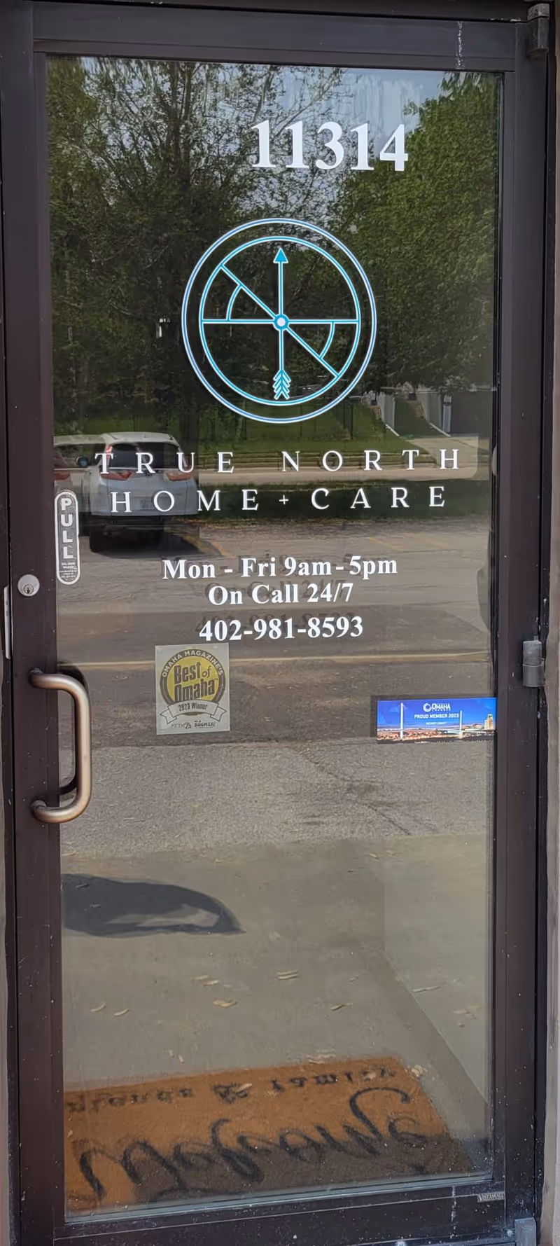 Glass entrance door for True North Home Care showing the logo, hours, and address 11314