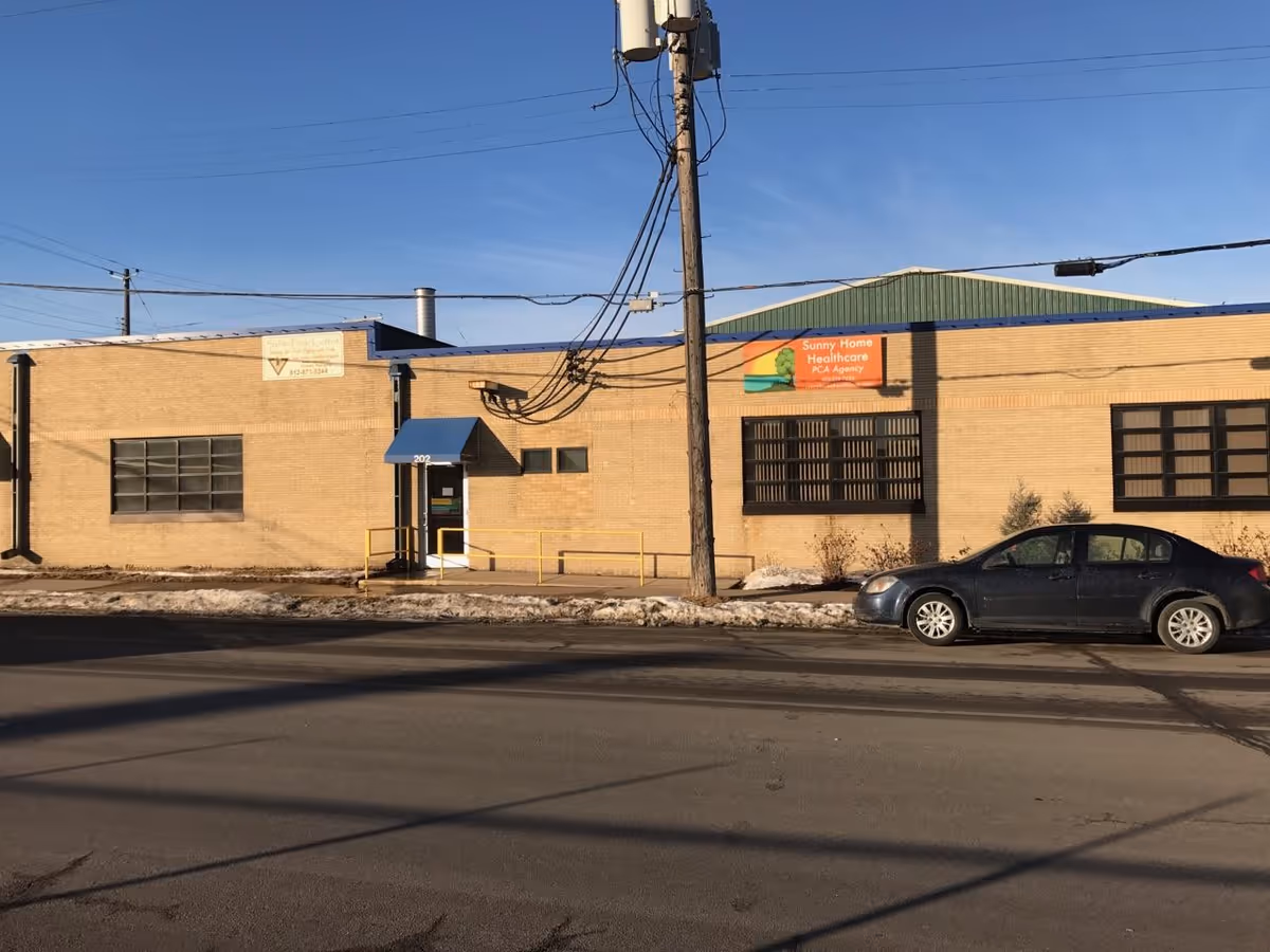 Street-level view of Sunny Home Healthcare building exterior with a parked car