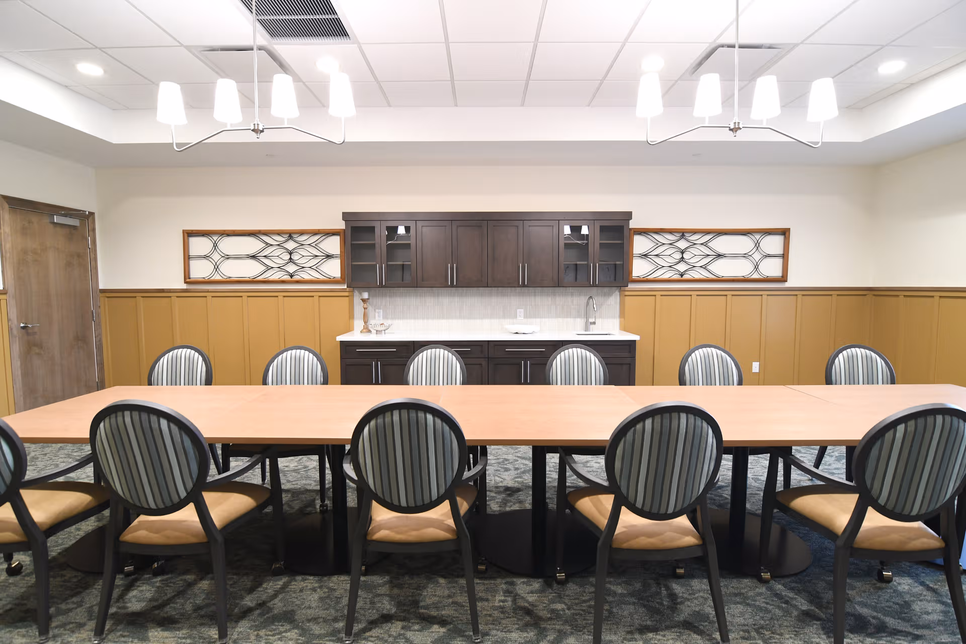 Large rectangular dining table with striped chairs in a formal communal dining room.