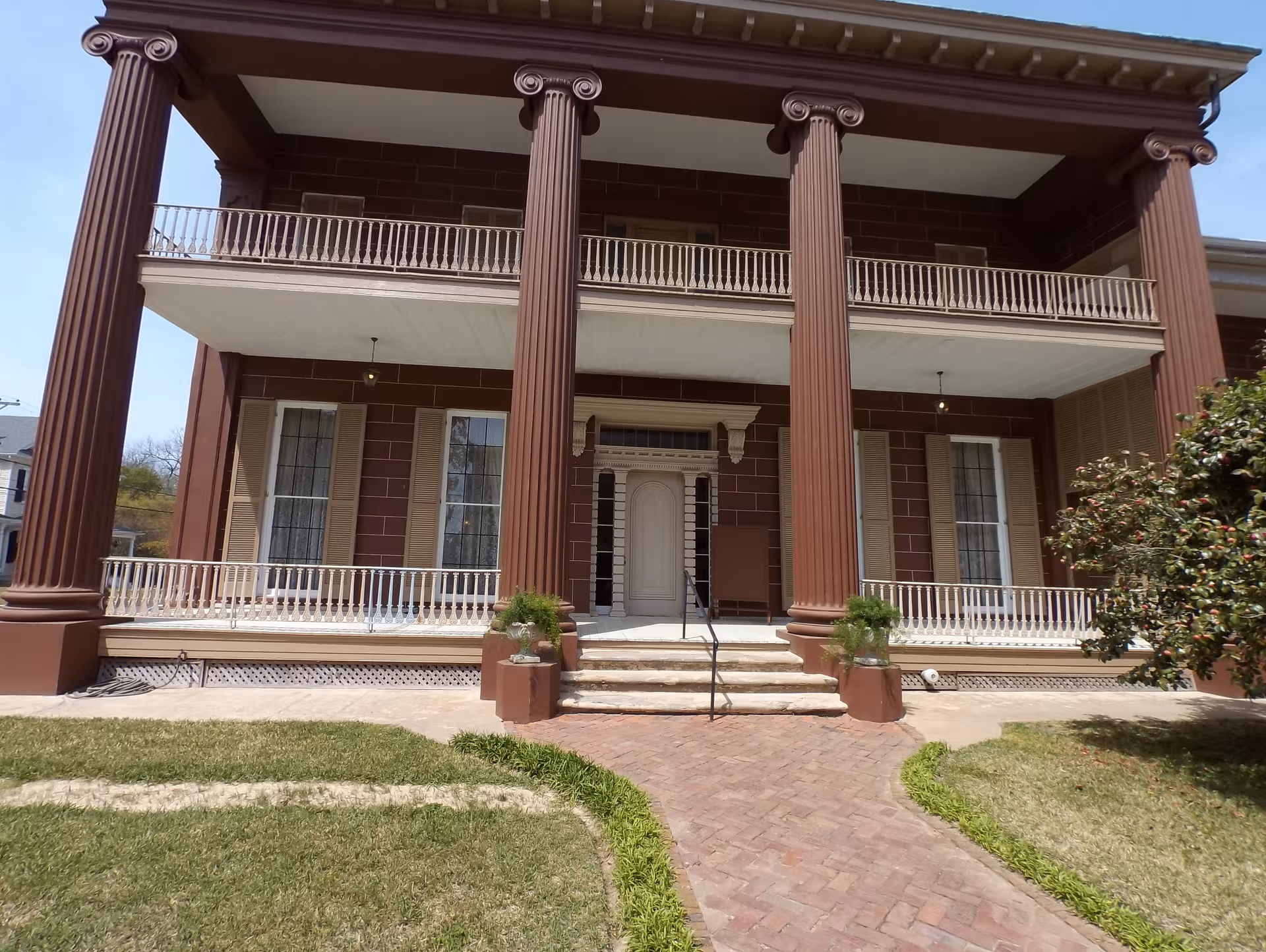A large brick building with tall columns and a wide front porch.