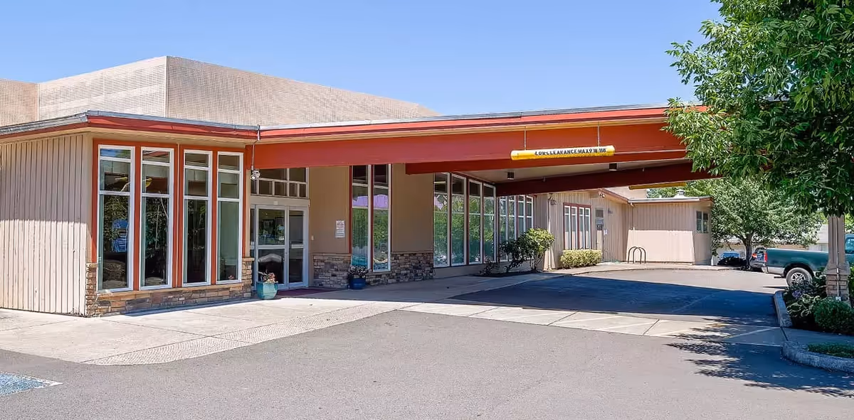 Outside view of Avamere Rehabilitation of Eugene entrance with a red canopy and parking area
