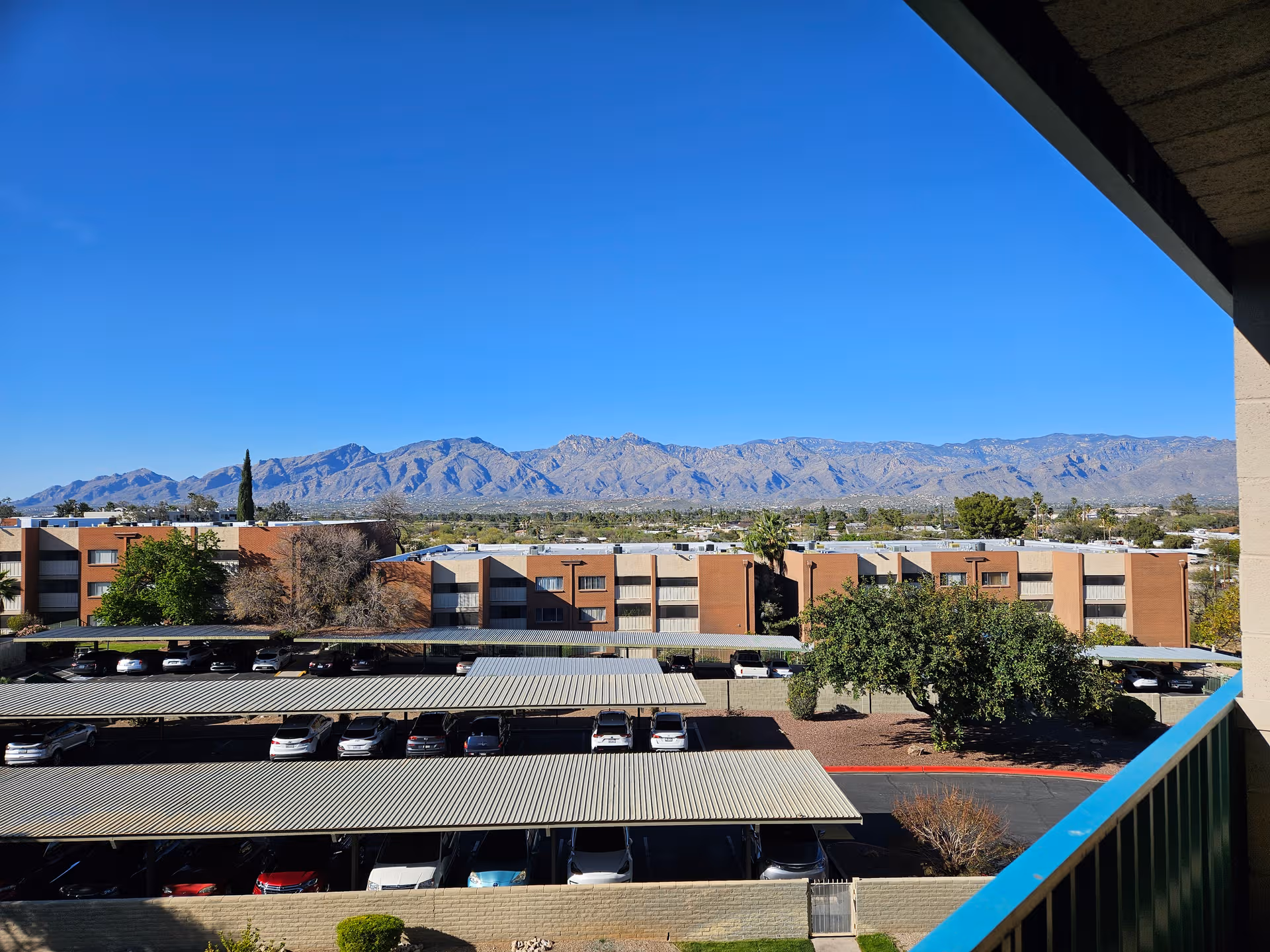 Exterior view of Cascades of Tucson buildings with parking and distant mountains.
