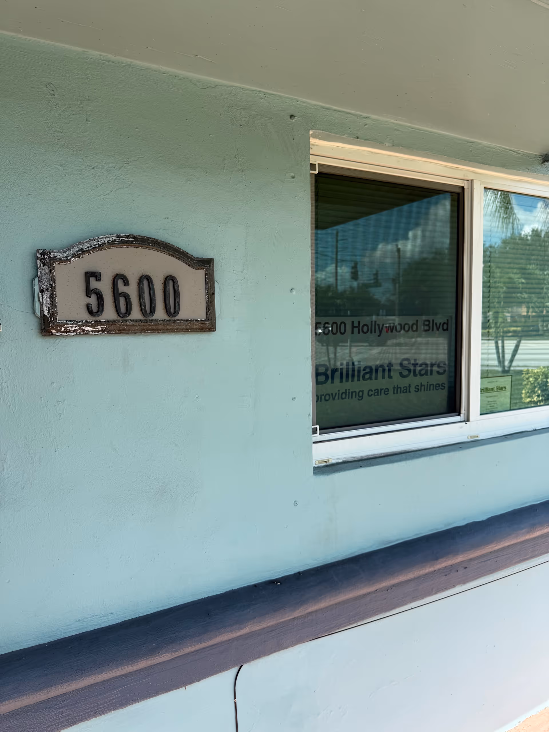 Light green building front with address plaque 5600 beside a window showing Brilliant Stars signage.
