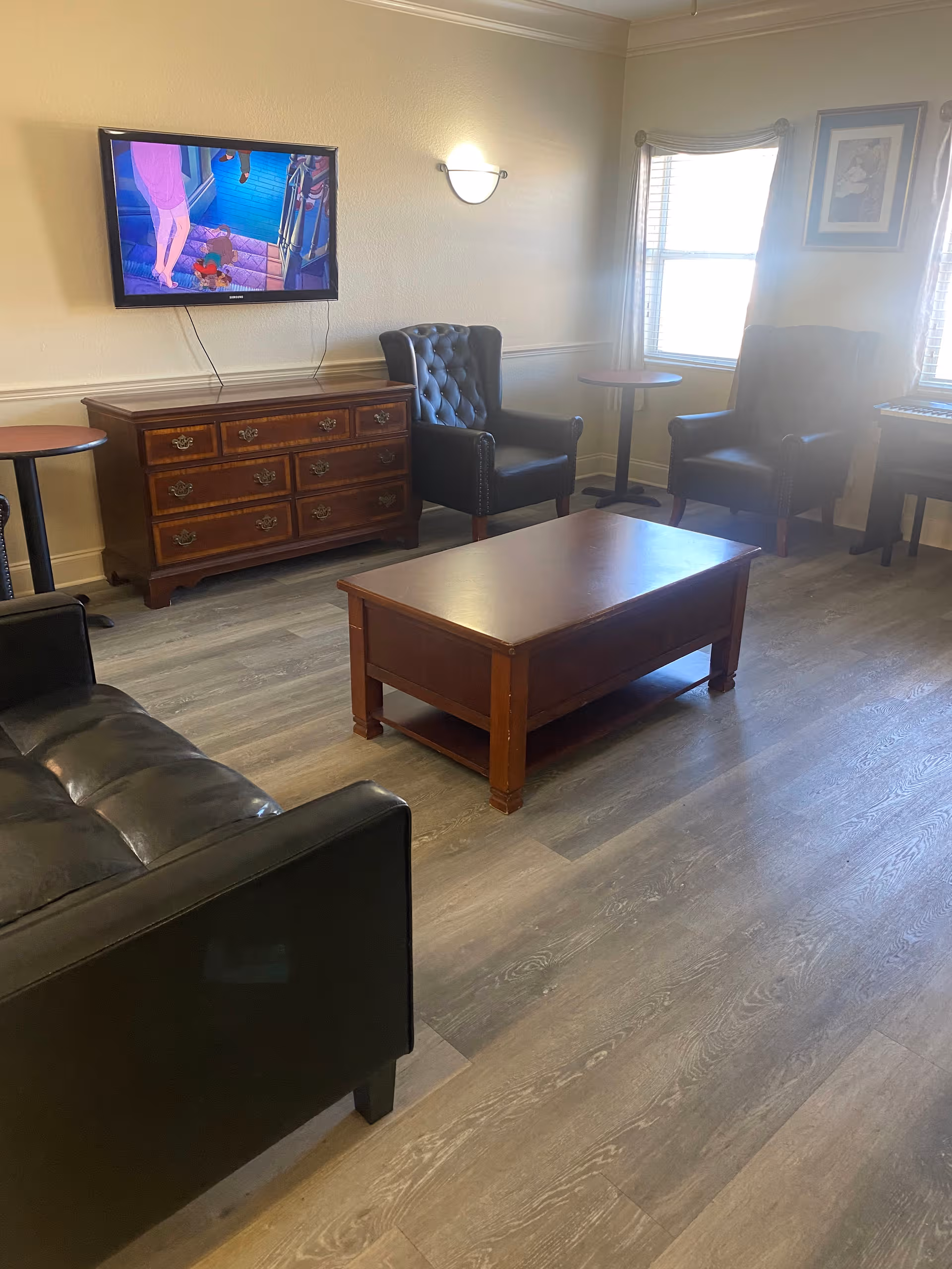 Cozy Harmony House living room with black leather chairs, wooden coffee table, and mounted TV.