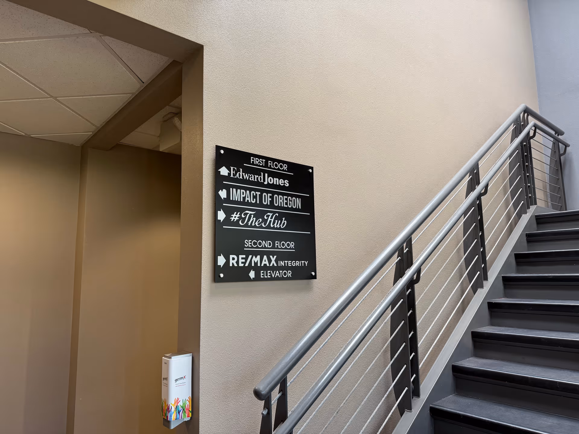 Interior stairwell with metal railing and wall-mounted directional sign.