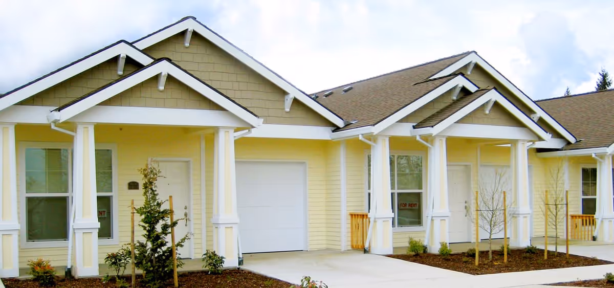 Row of light-yellow, single-story townhomes with white trim and covered entry porches.