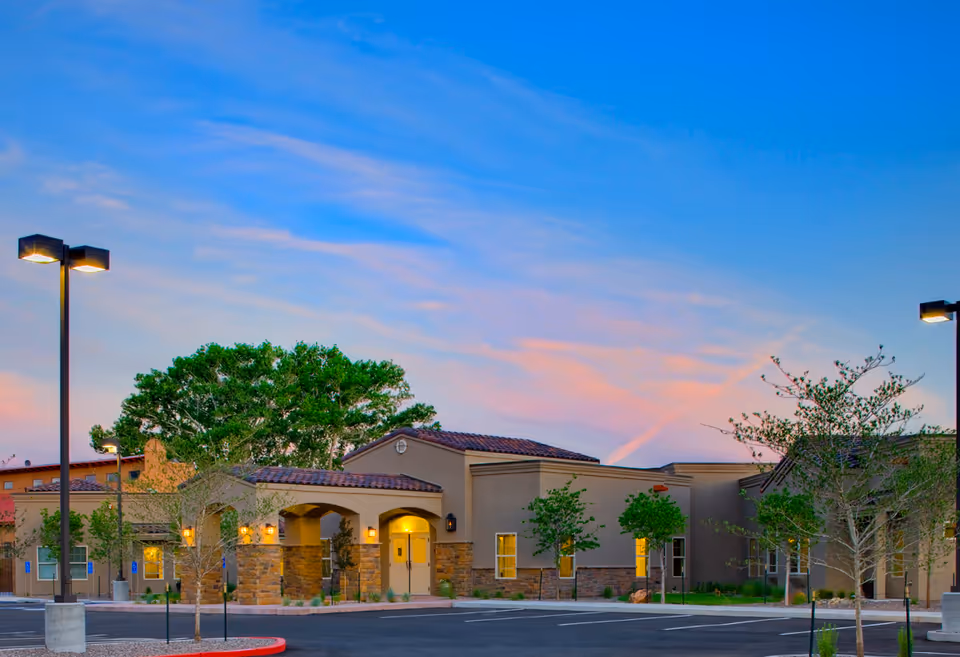 Exterior view of Retreat Gardens senior living facility with arched entrance at sunset.