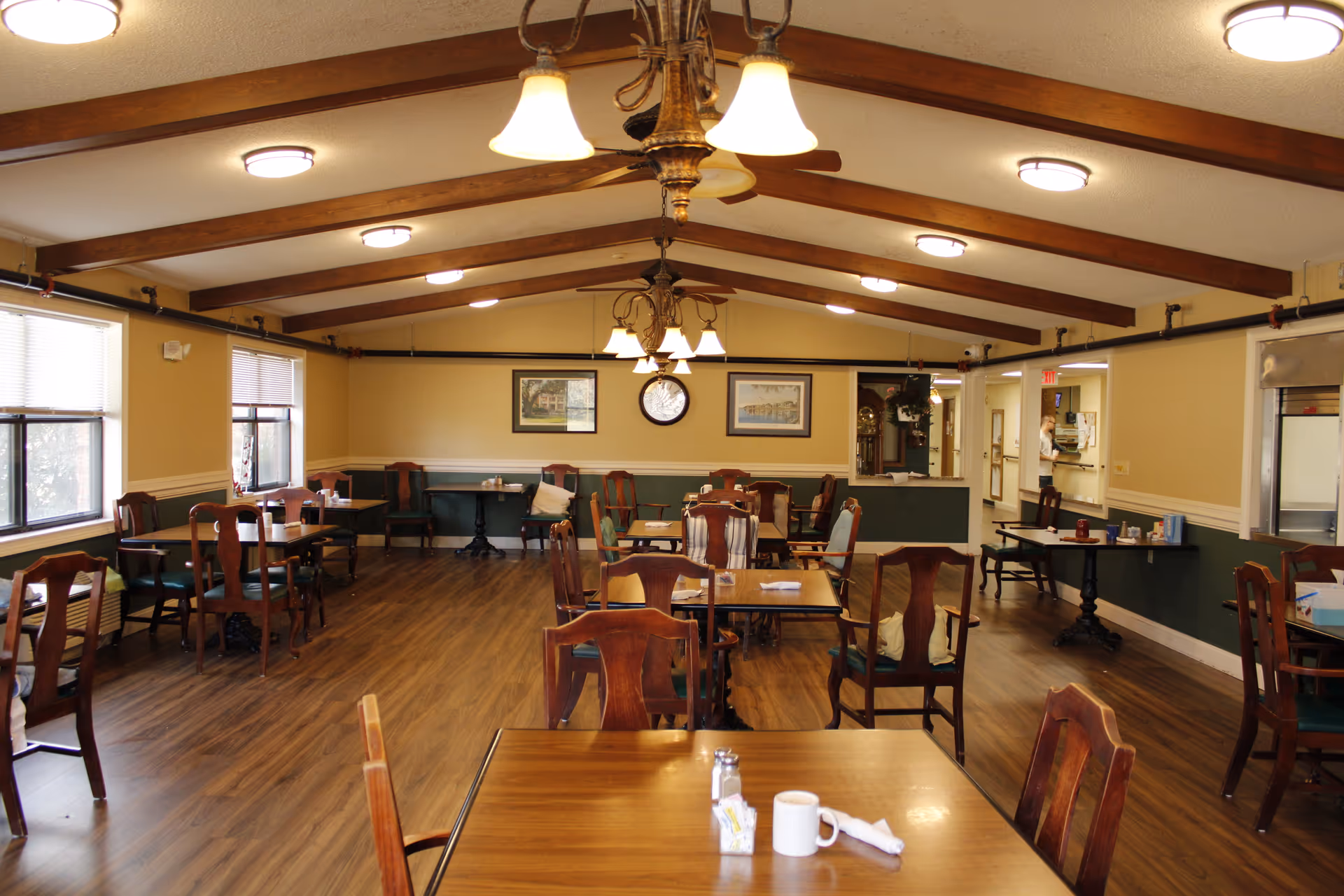 Spacious dining room with wooden tables and chairs under warm lighting.