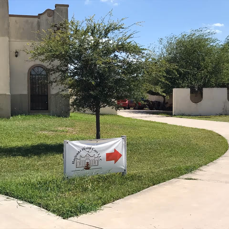 Exterior view of Hacienda Health Care facility with a sign along curved sidewalk.