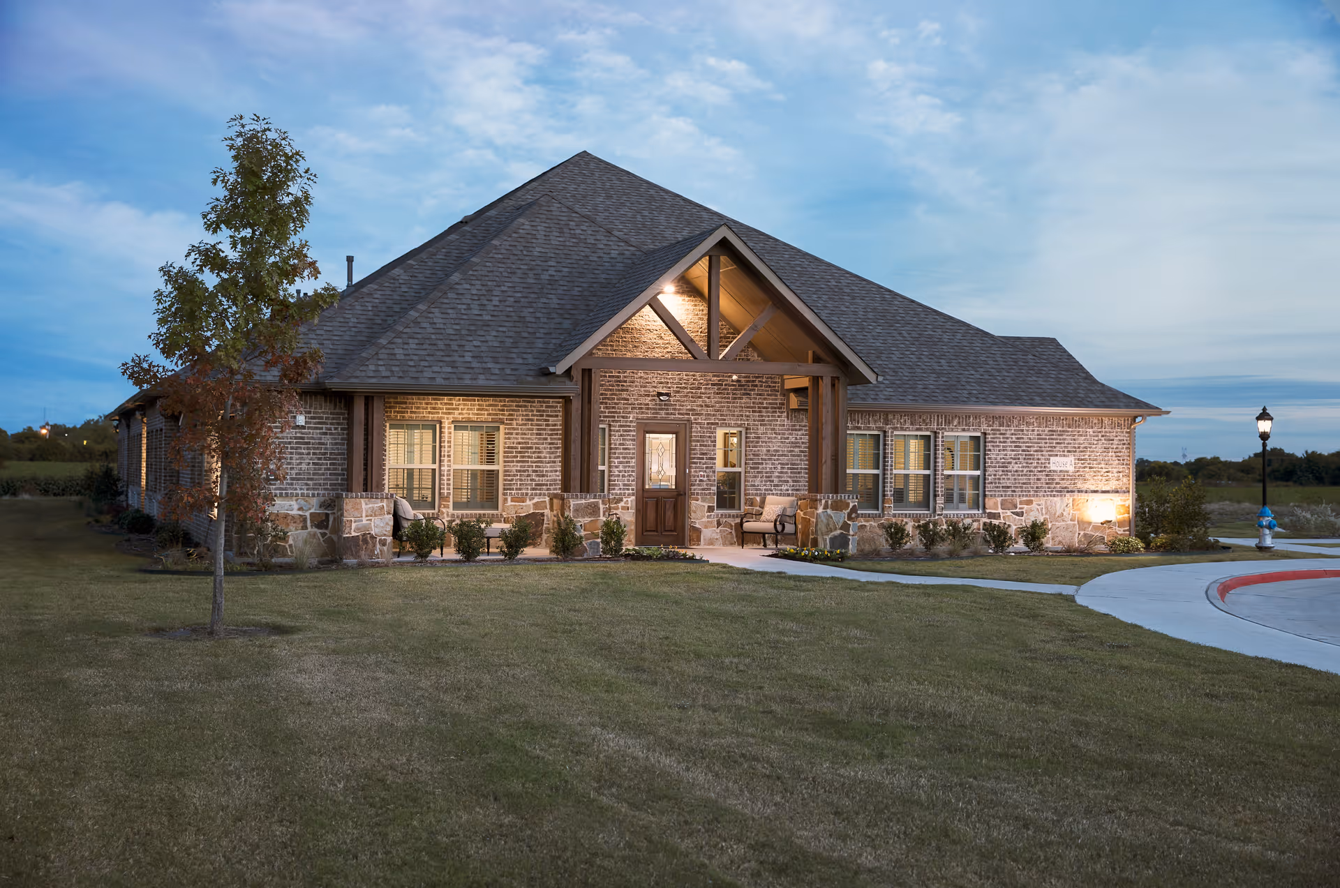 Front view of a brick senior living facility with a manicured lawn and entrance.