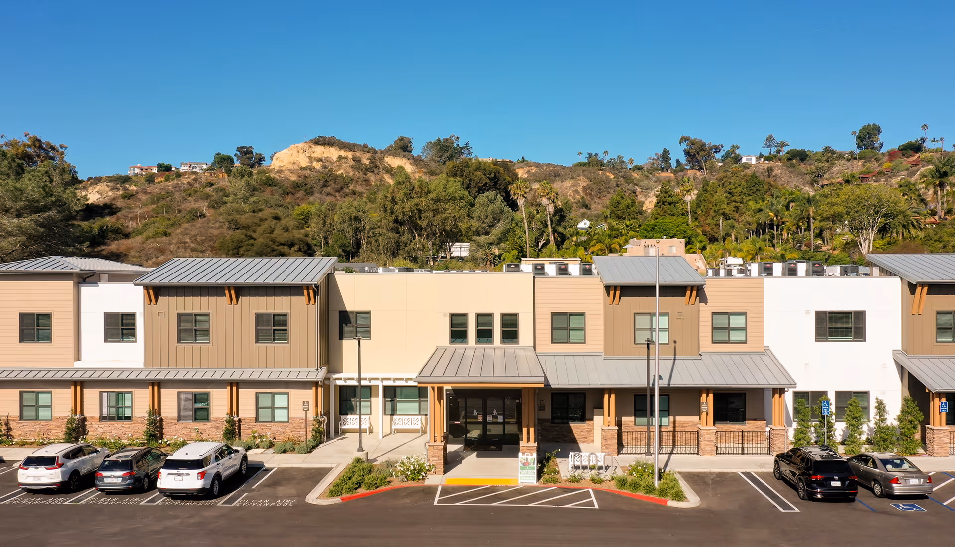 Exterior view of Westmont of Encinitas, a multi-section senior living facility with a parking lot.